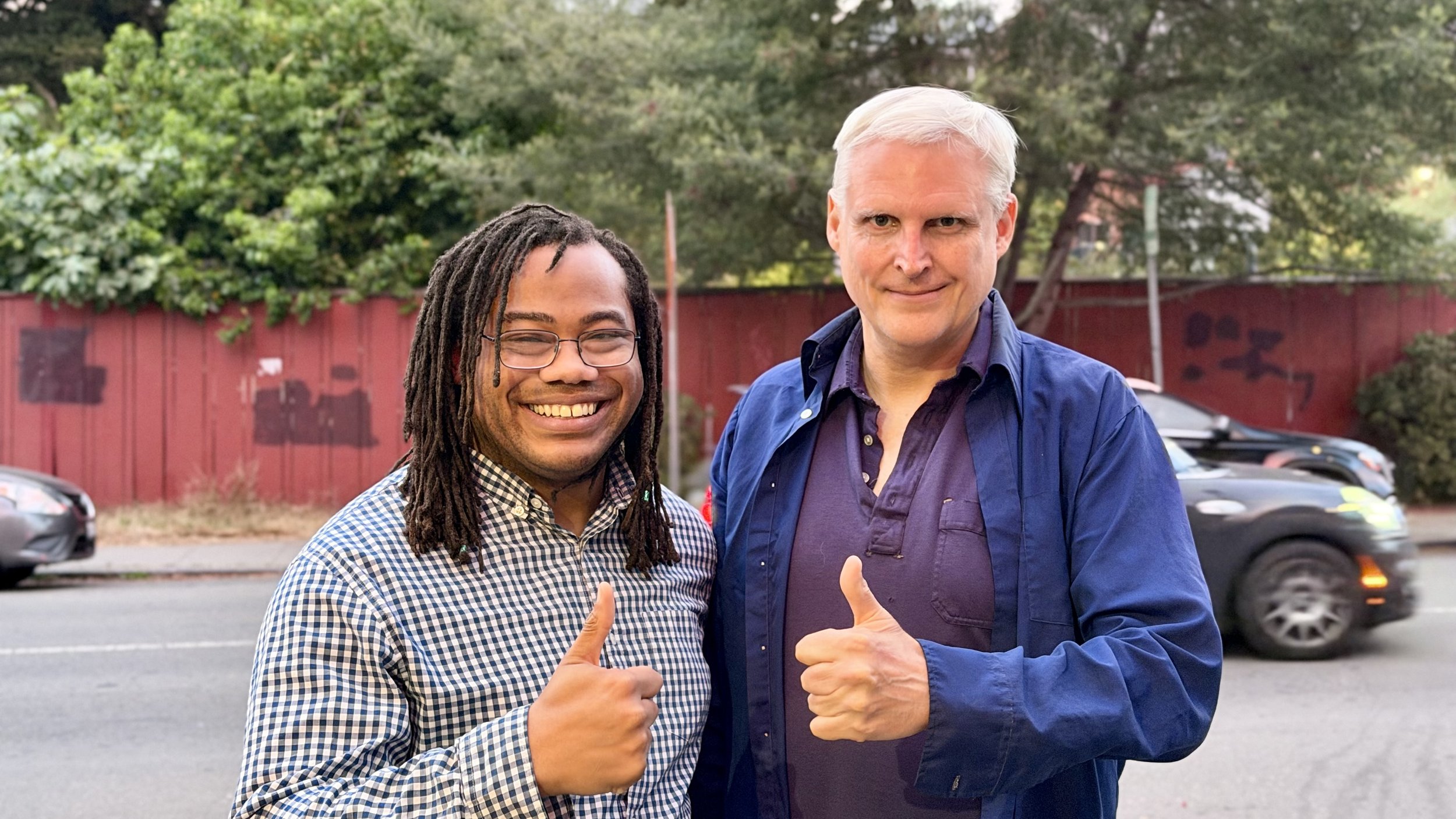 Aidan Hill with a Berkeley community supporter giving thumbs up outdoors.