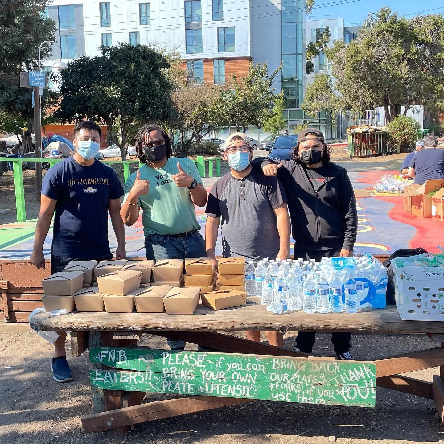 Volunteers at an outdoor food and water table during a community mutual aid event.