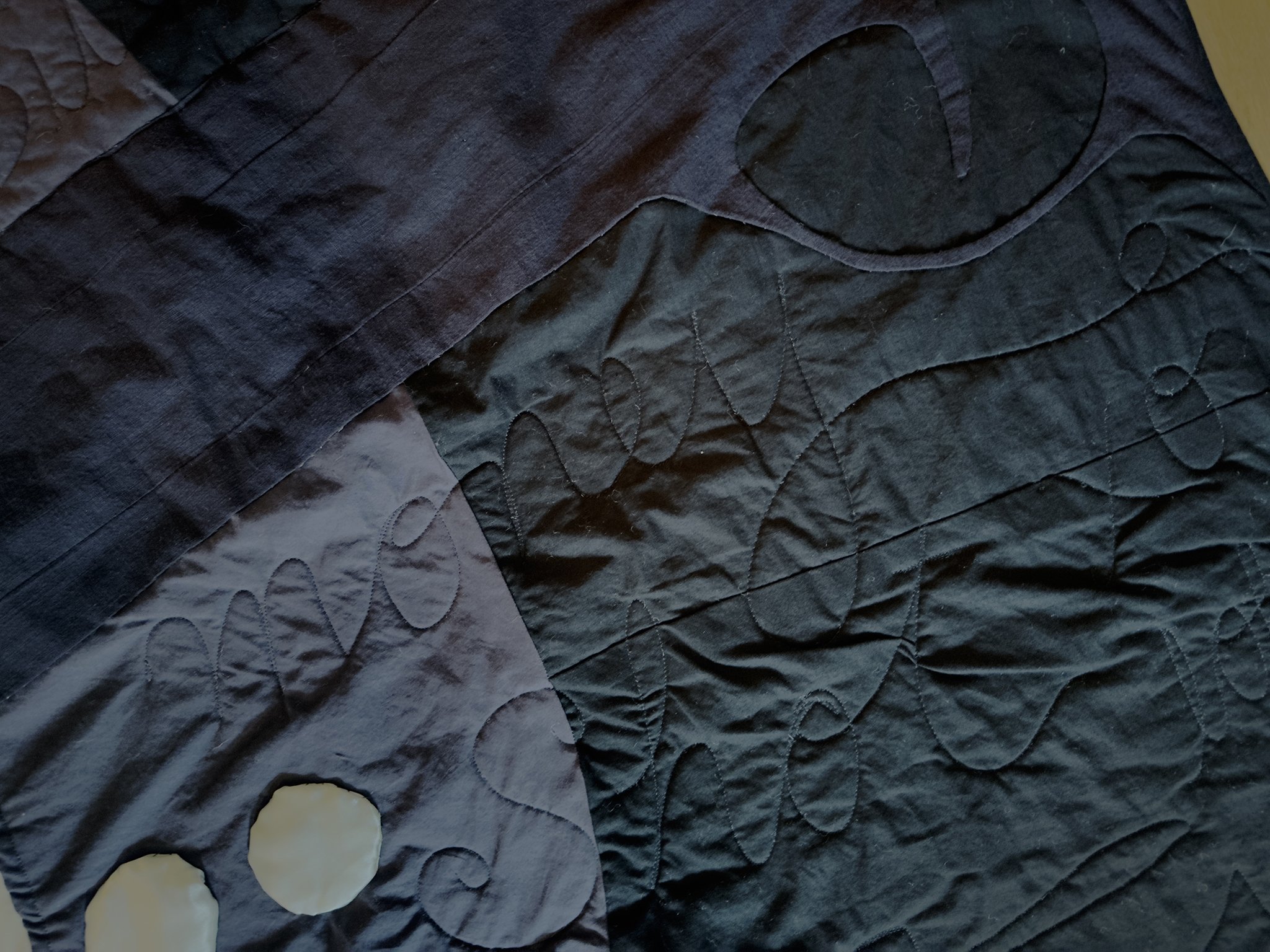 Close up of Dowry quilt showing black hand gun and "money shot"--the text is quilted on in cursive.