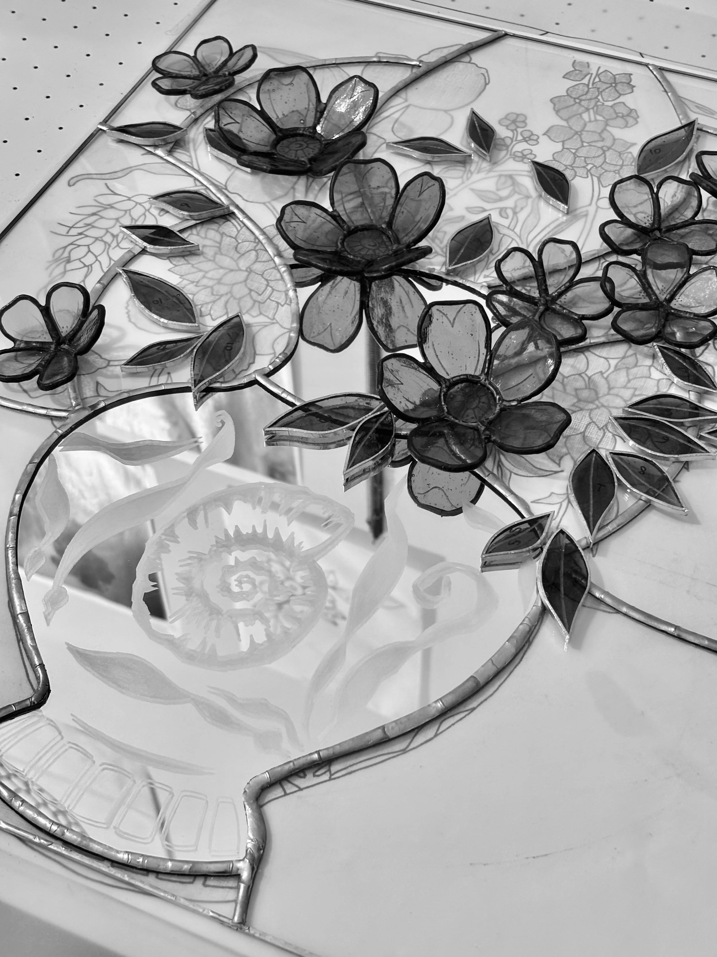 Detail of a Glass By Butler and tattoo artist Rebecca Vincent collaborative artwork combining mirrored surfaces with hand-cut stained glass flowers and leaves.