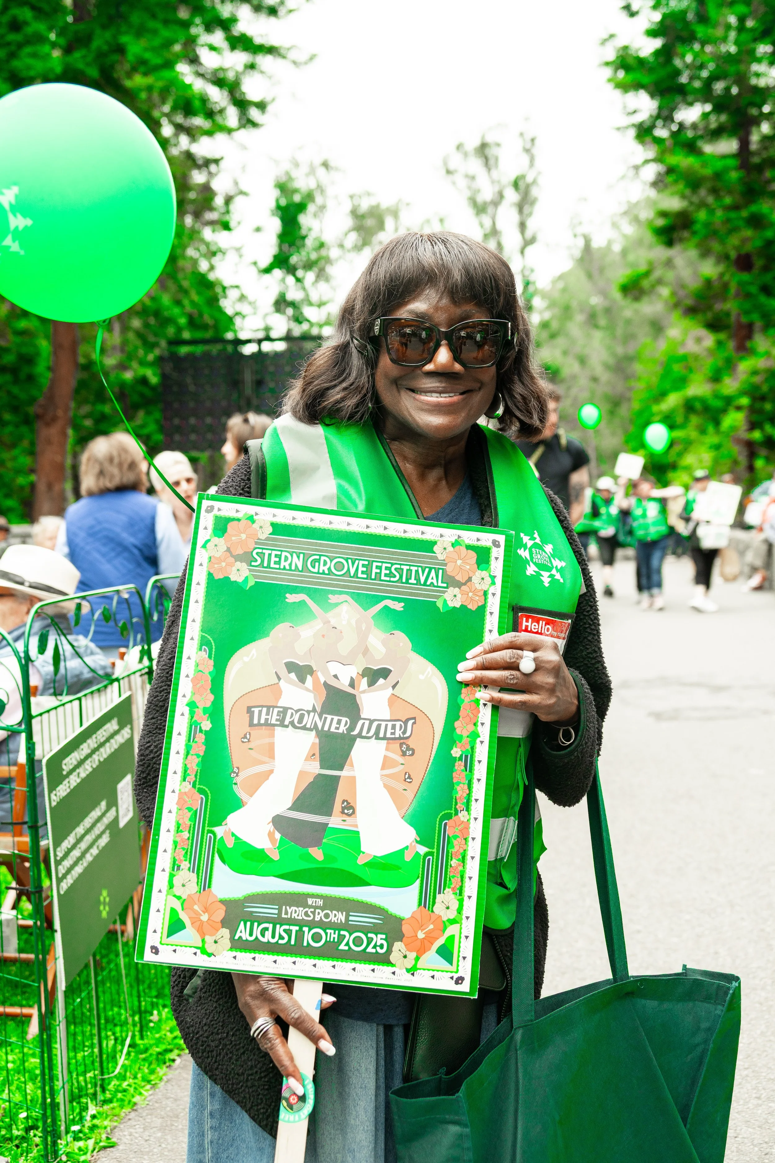 male volunteer for stern grove holding out a donation bucket to crowd