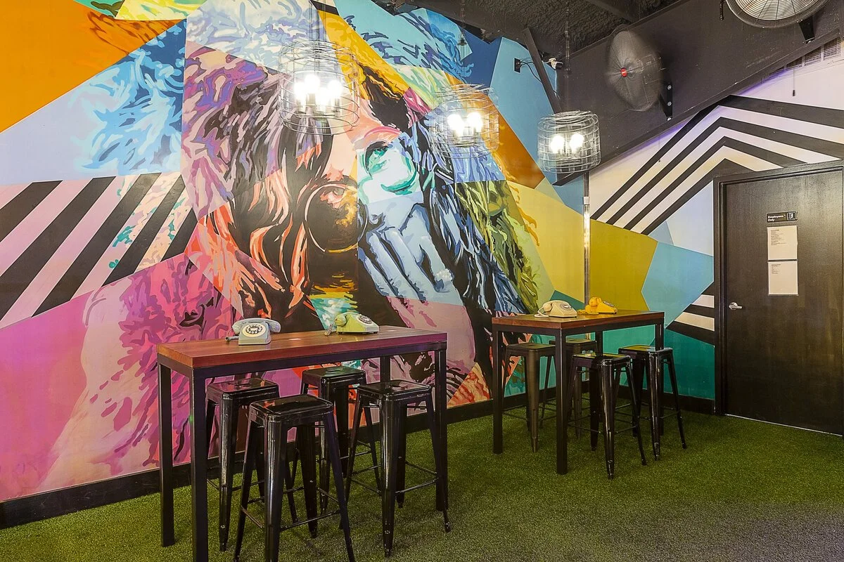 Colorful graphic mural of Janis Joplin in fur hood looking upward