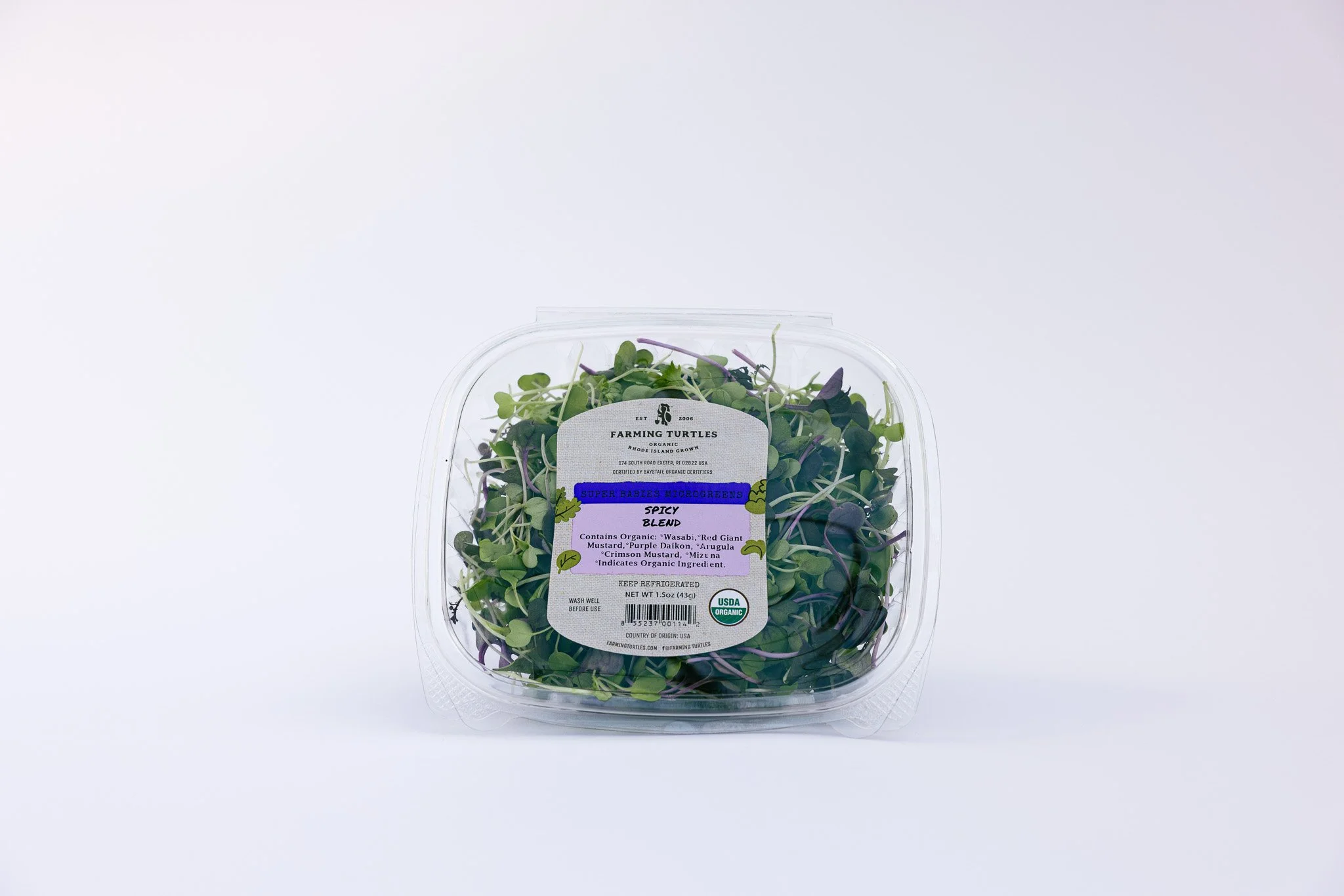 Clear plastic container of microgreens labeled 'Farmington Turtles' with organic labeling and a mix of green and purple leafy microgreens inside.