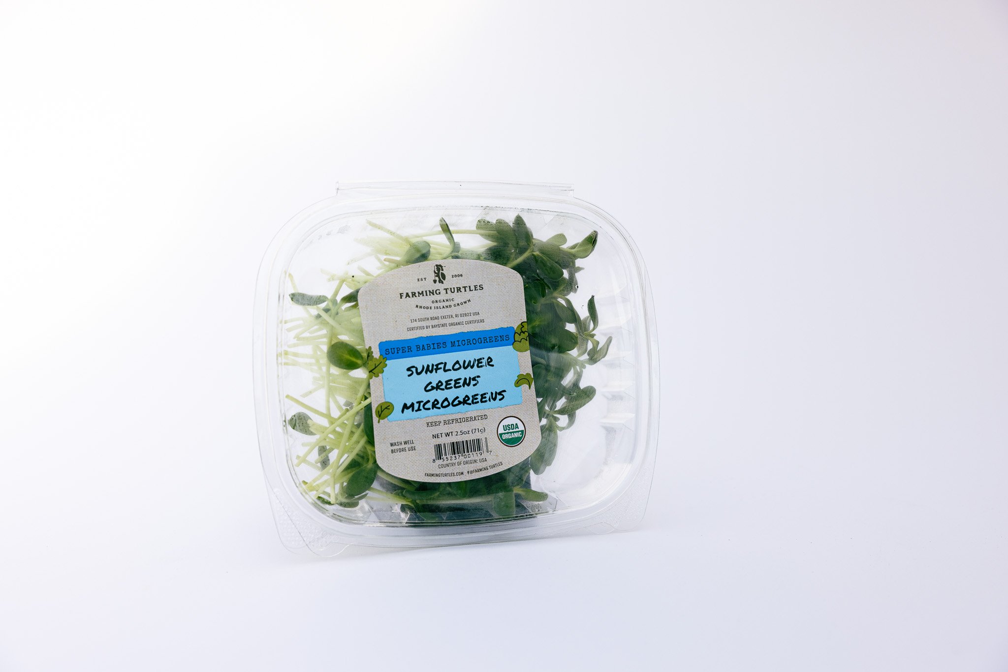 Plastic container of sunflower greens microgreens with a white and blue label.