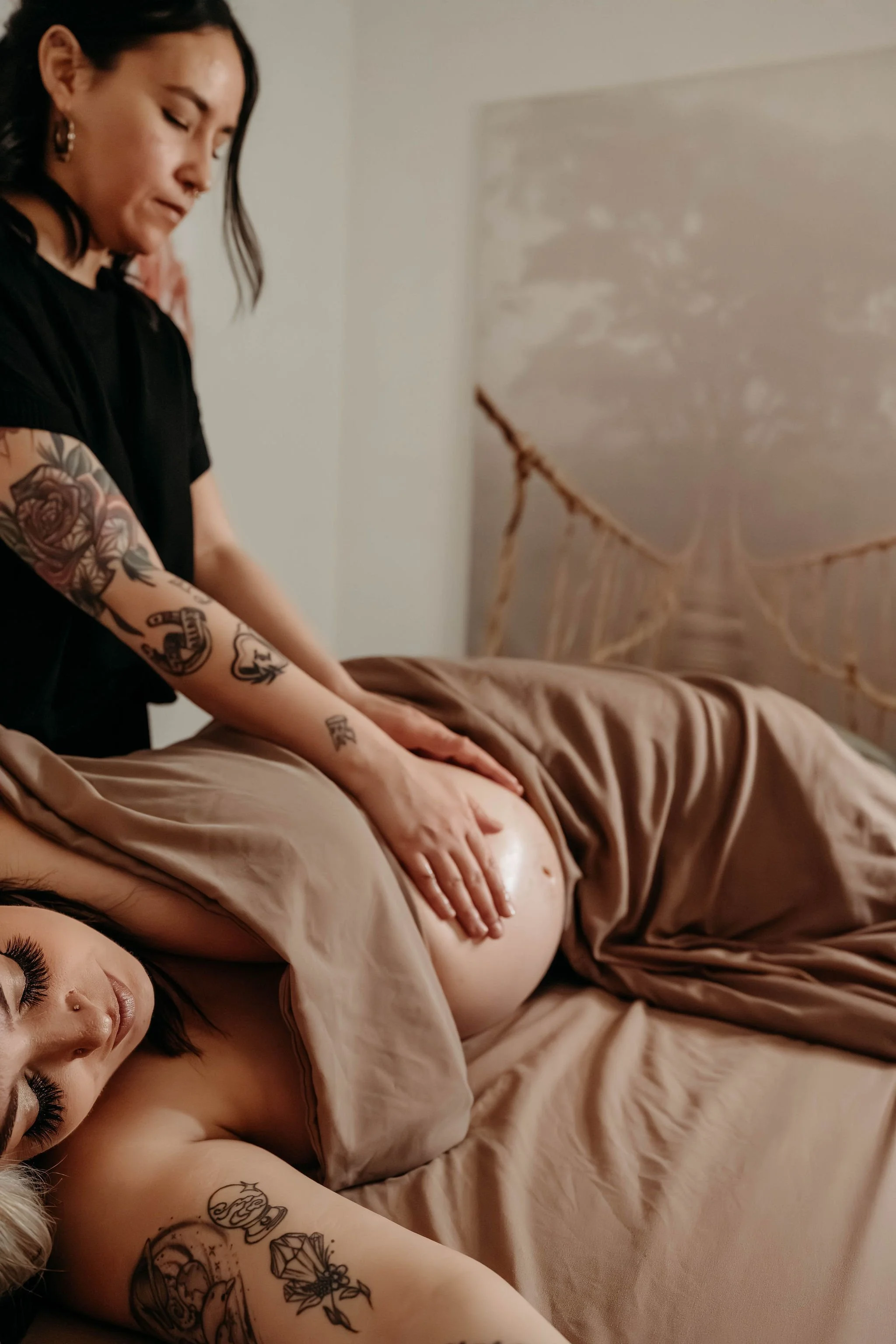 A woman side-lying on a bed receiving a pregnancy massage.