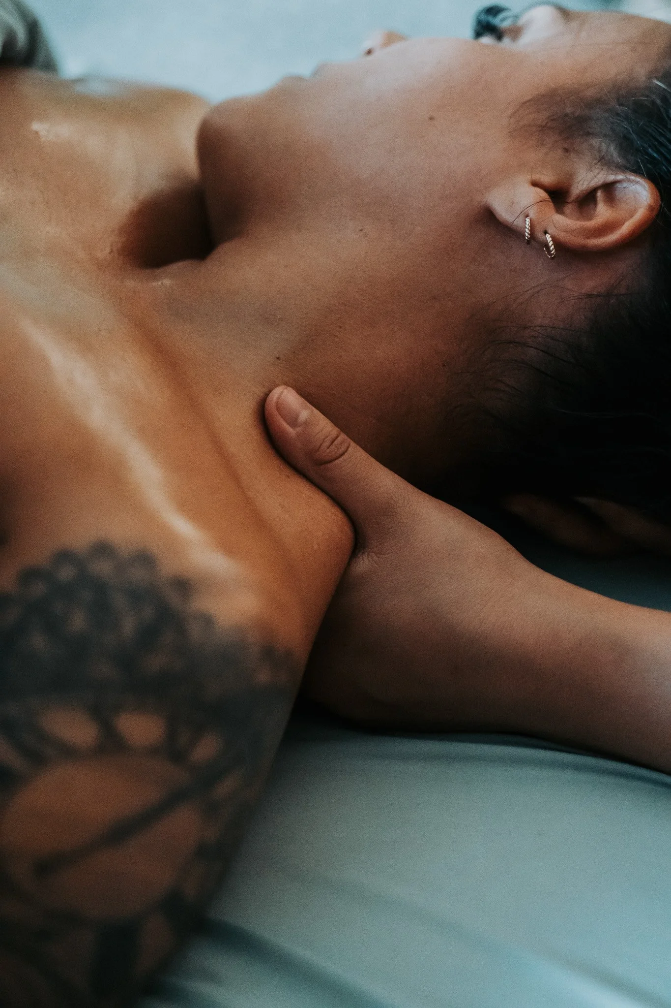 A woman lying down, holding her head, with her eyes closed and a peaceful expression on her face.