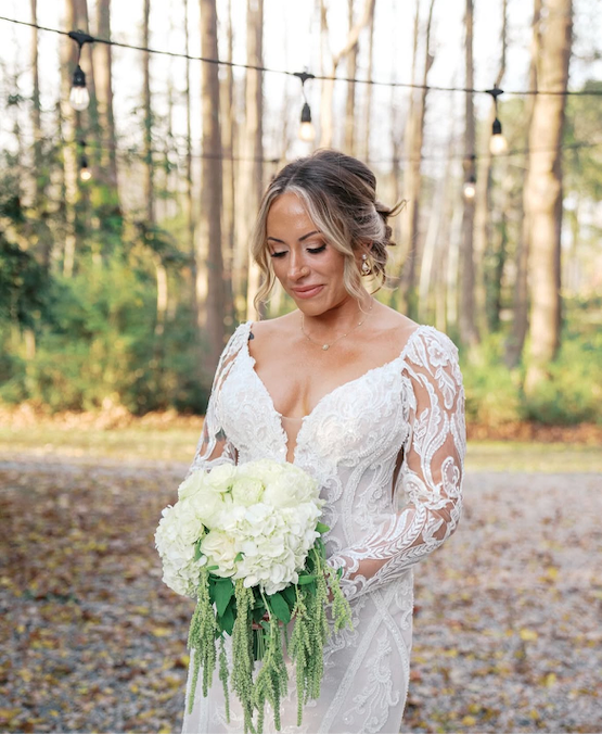 Editorial bridal updo with soft face-framing curls and a white floral bouquet for a luxury outdoor wedding in North Carolina.