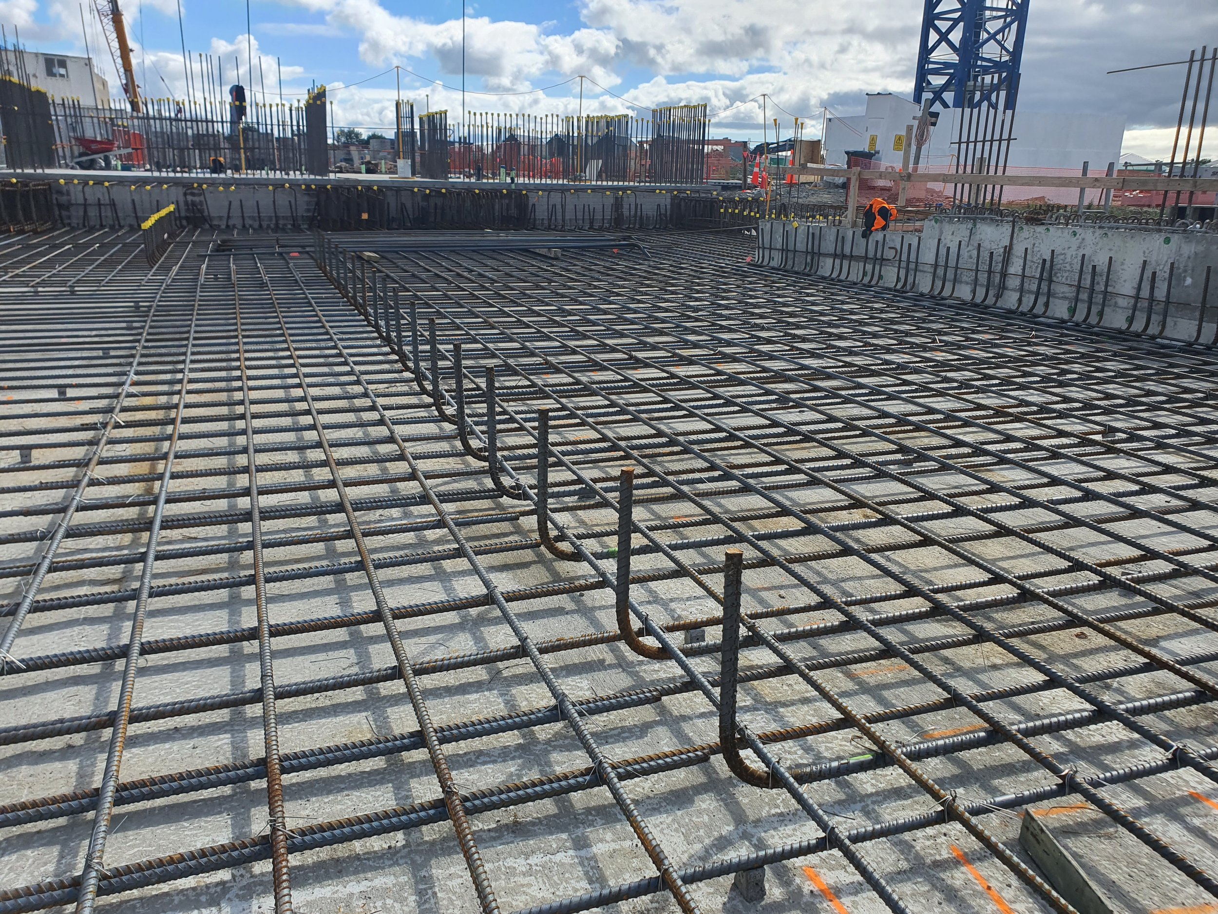 rebar steel on worksite in grids with people working in the background