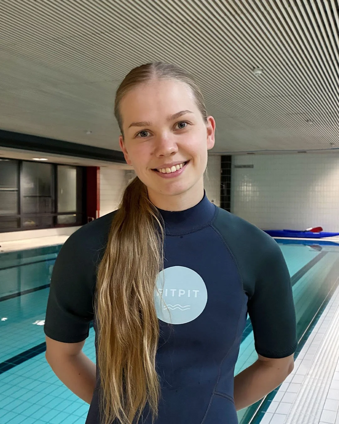Hymyilevä naispuolinen uinninohjaaja uima-altaalla
