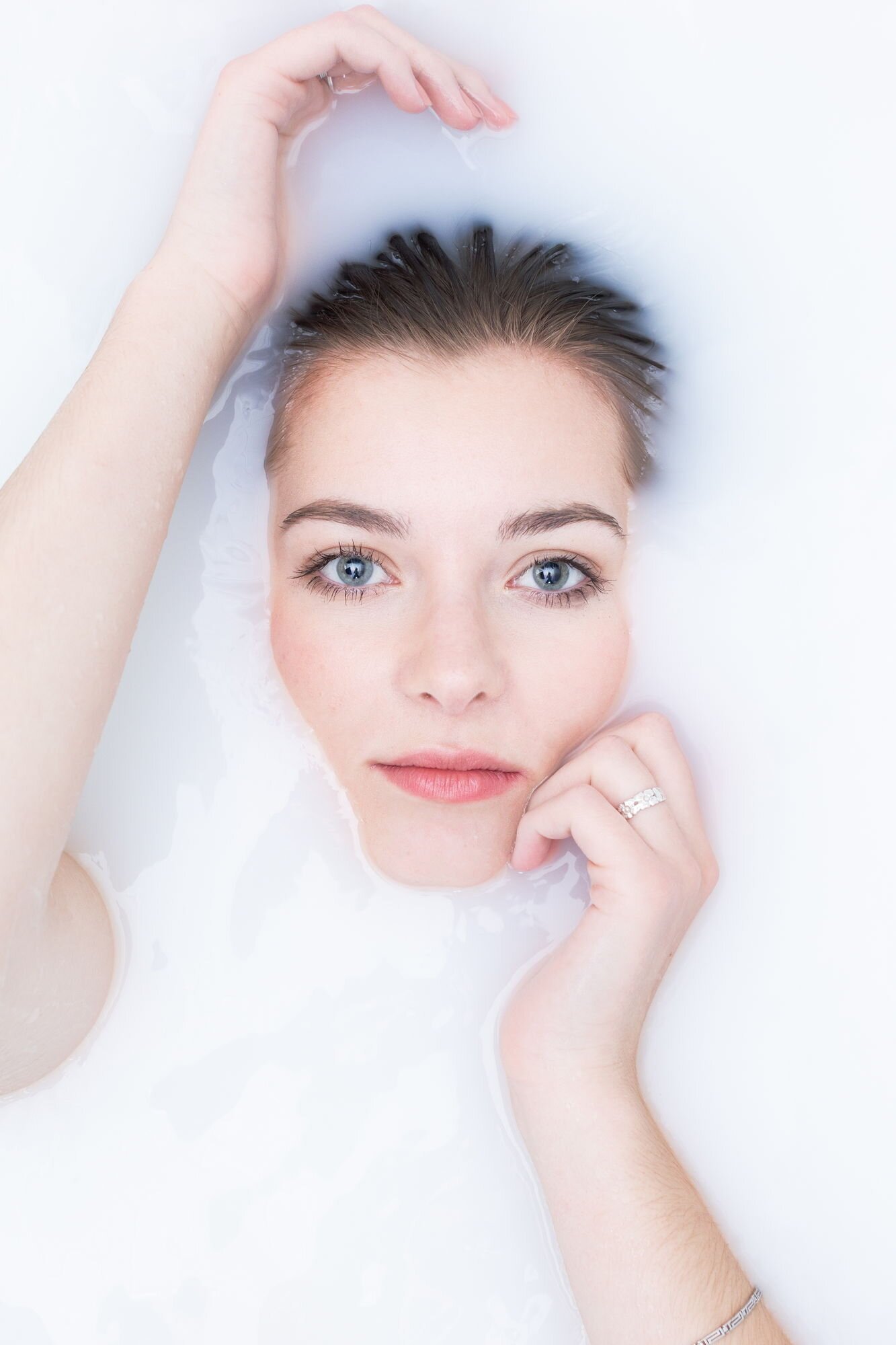 Nahaufnahme eines Mädchens mit blauen Augen, das in Milch badet.