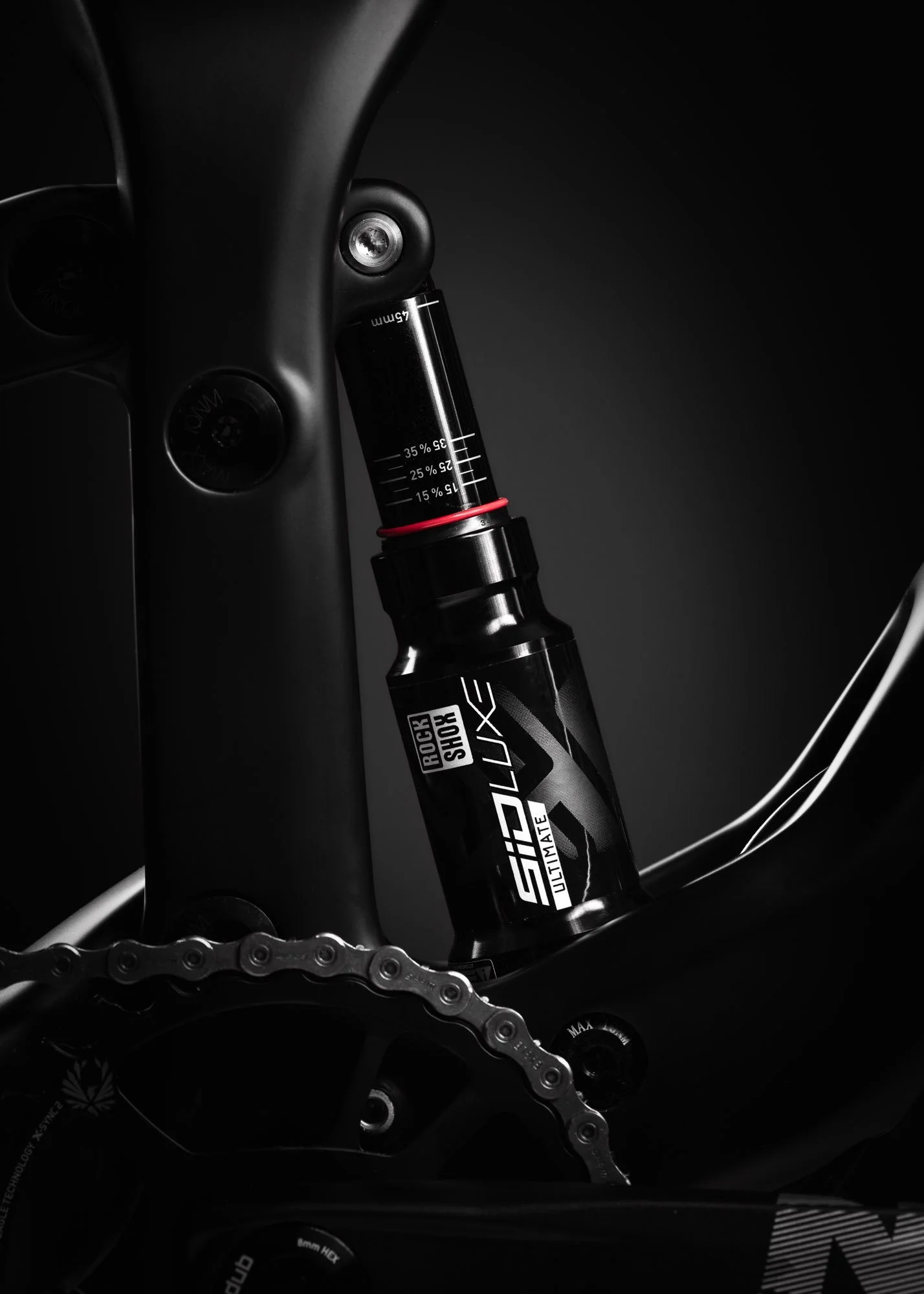 Nahaufnahme einer schwarzen RockShox Sid Ultimate Federgabel an einem Fahrradrahmen, mit Fokus auf die Dämpfer im dunklen Umfeld.