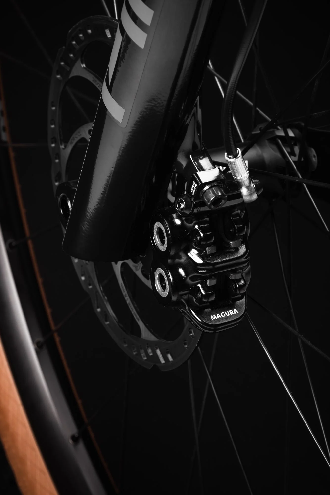 Nahaufnahme eines schwarzen Fahrradnaben und -bremsers mit der Aufschrift MAGURA, Fahrradrahmen und Felge im Hintergrund.