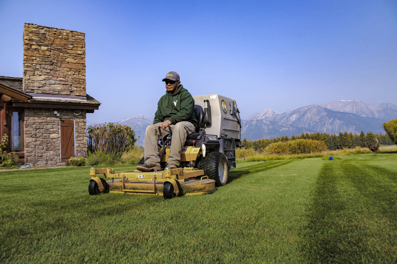 Landscaper on a mower with the Teton range behind