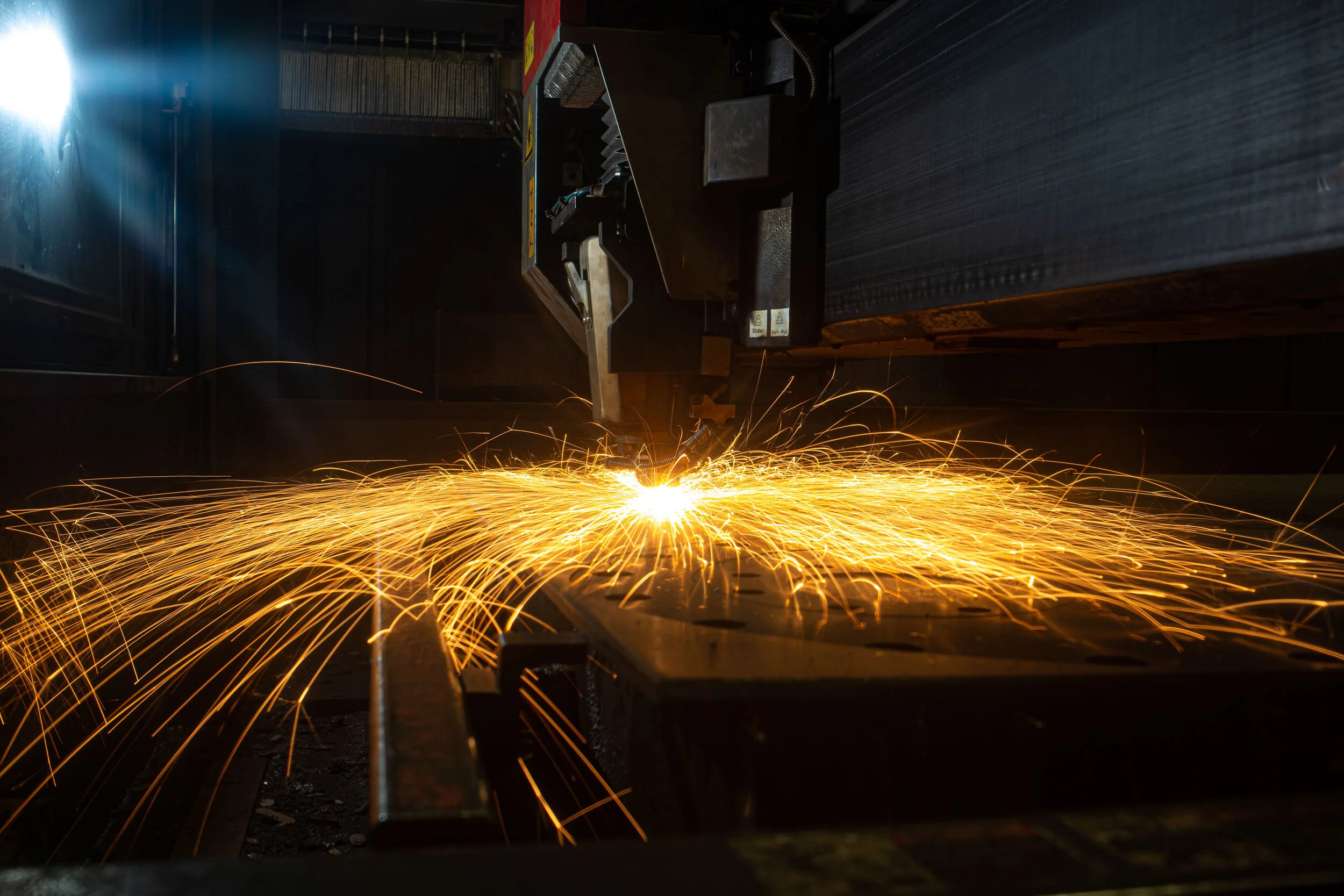 Plasma cutter throwing a fan of sparks across a steel table