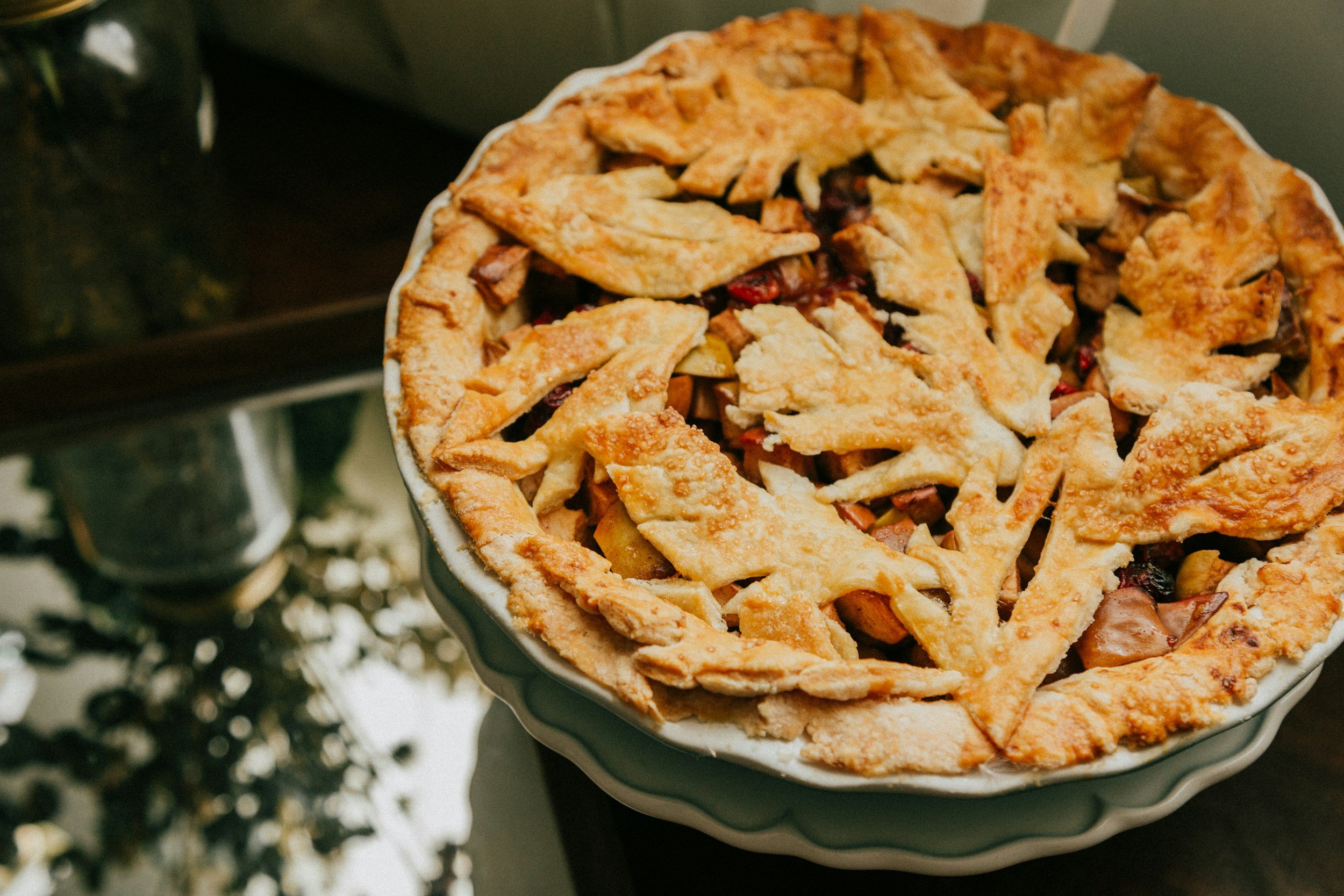 A freshly baked fruit pie in a ceramic dish, featuring a lattice crust with a slightly golden crust and filling of mixed berries and fruits.