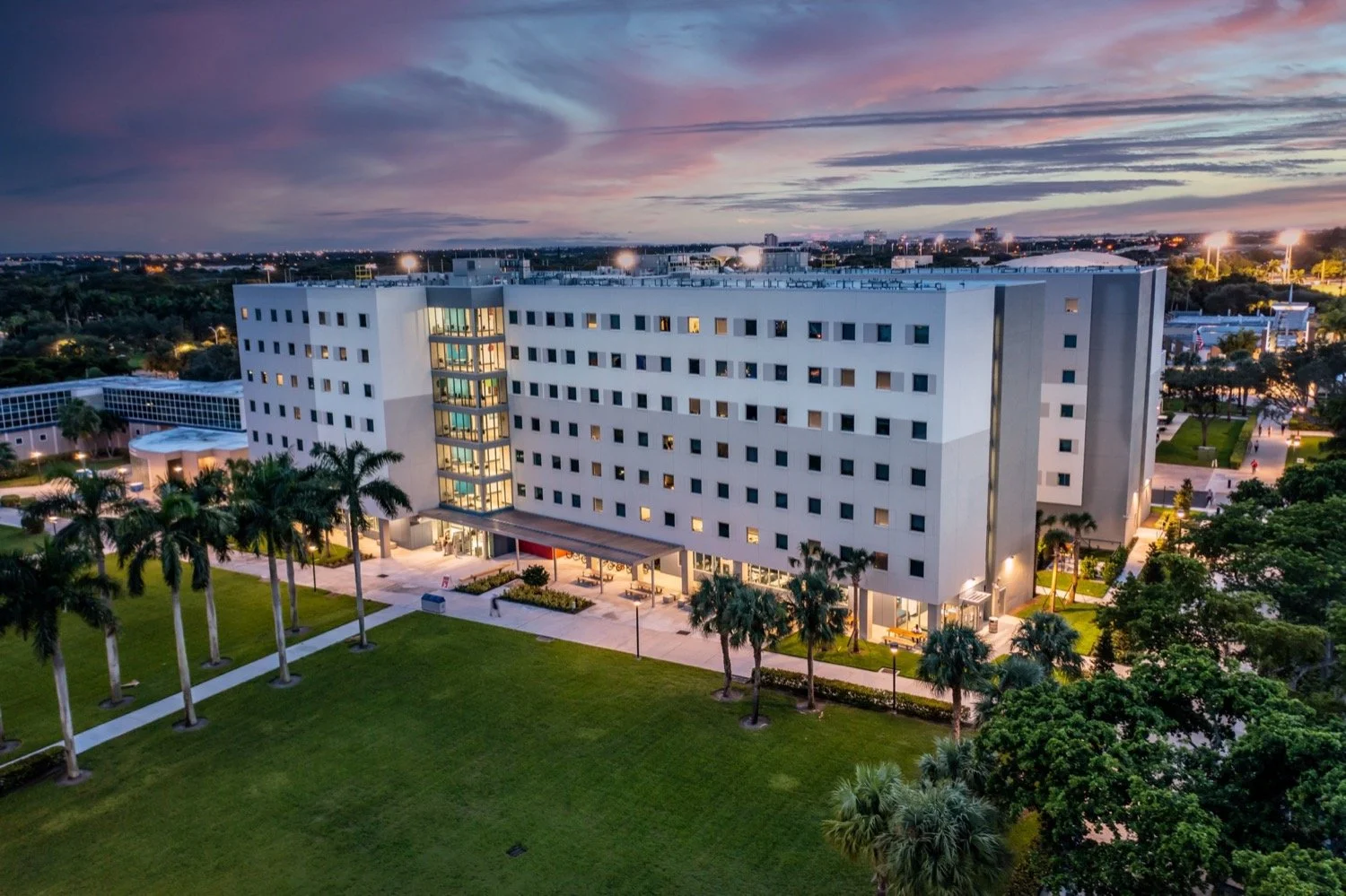 Aerial photograph of a multi-story property at dusk, showing the roof and surrounding grounds