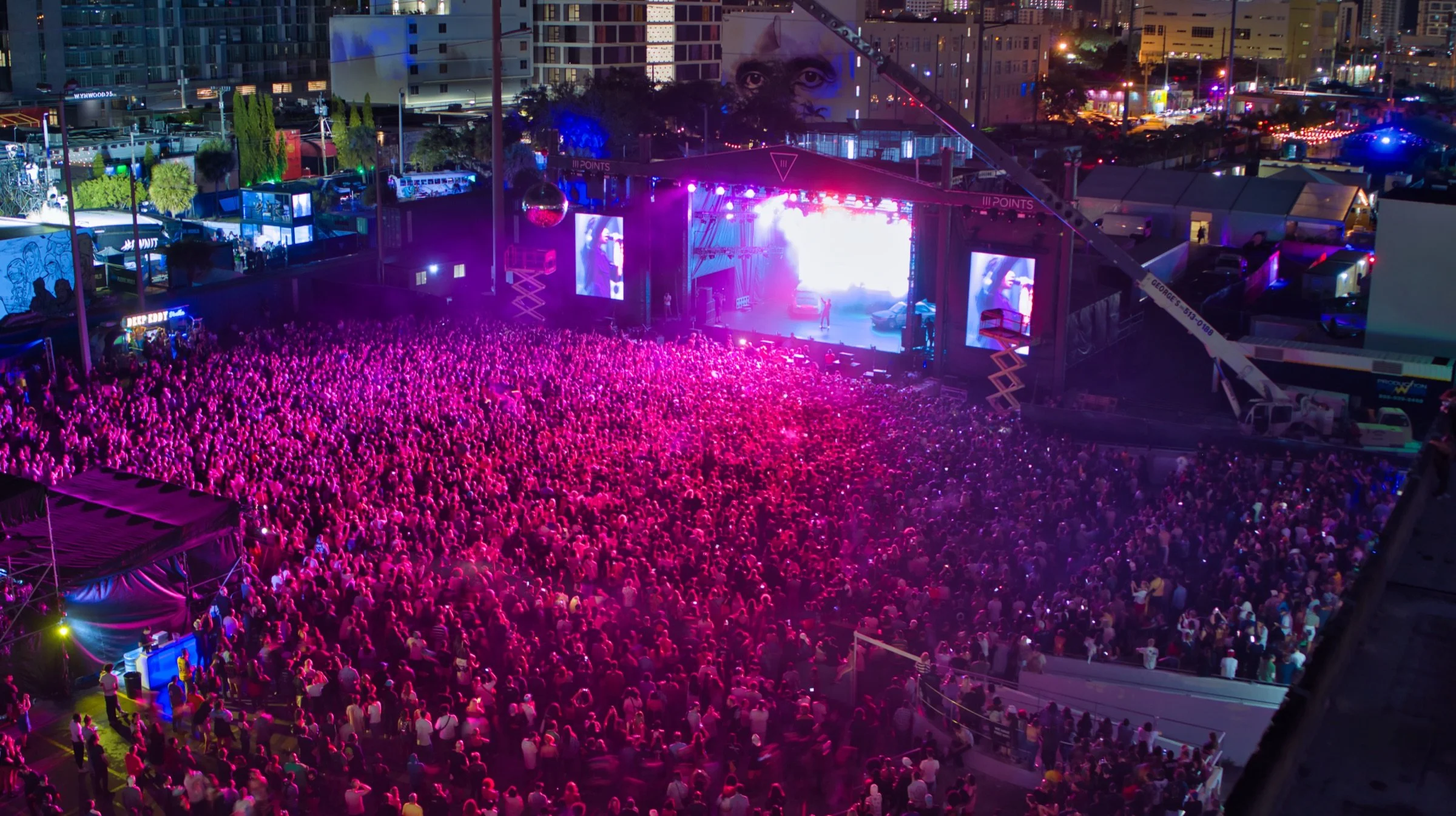 Aerial photograph of an outdoor concert crowd and stage at night
