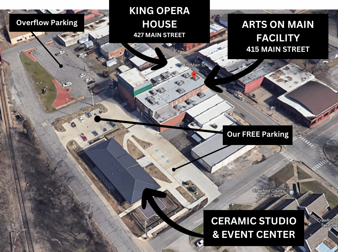 Aerial view of a commercial area with labeled buildings and parking areas. The King Opera House at 427 Main Street is in the center, with an Arts on Main Facility at 415 Main Street nearby. There are designated overflow parking, free parking, and a ceramic studio and event center with parking. The image shows roads, sidewalks, and some buildings, with labels pointing to their locations.