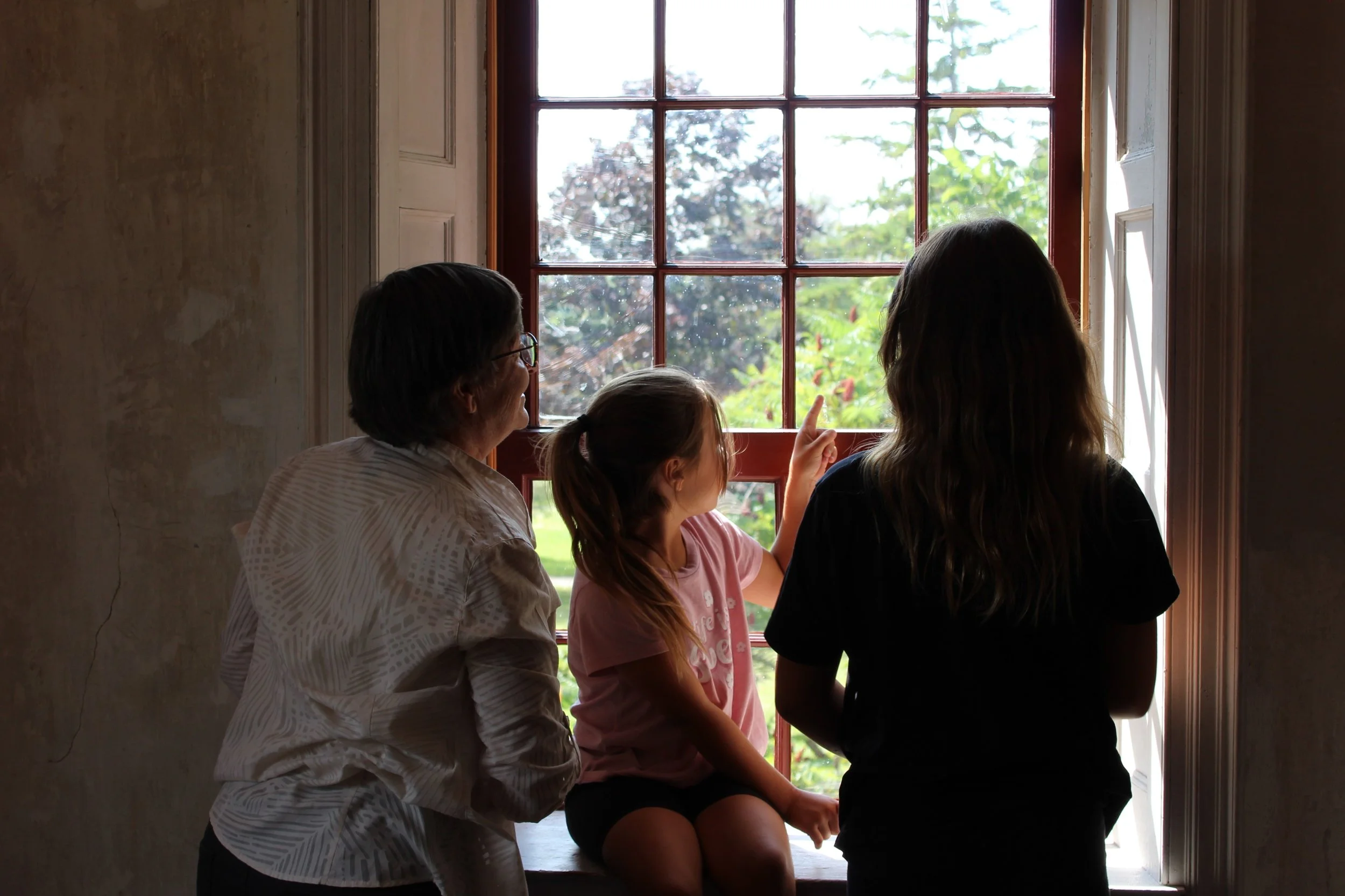 A family points out a window of a historic home.