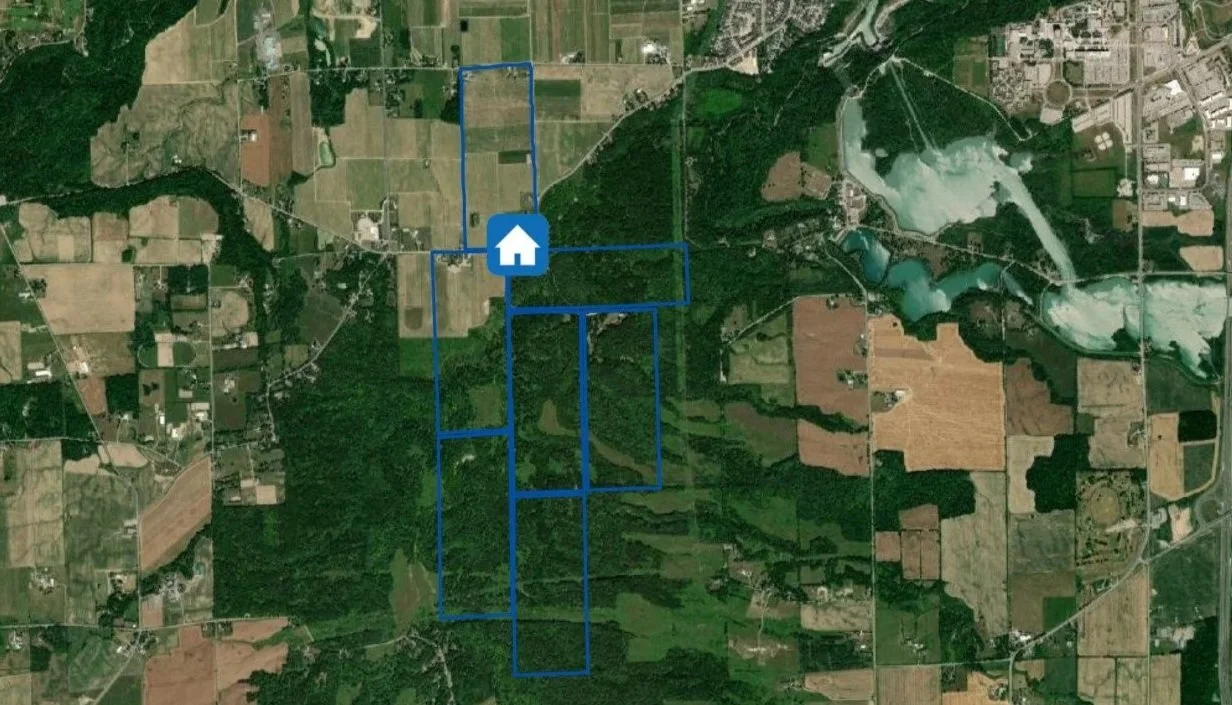 Satellite map of the land surrounding The Brown Homestead, mainly forest and farmland. Blue rectangles are overlaid onto the map marking the seven 100 acre parcels granted to John Brown. A blue house icon marks the location of the Homestead.
