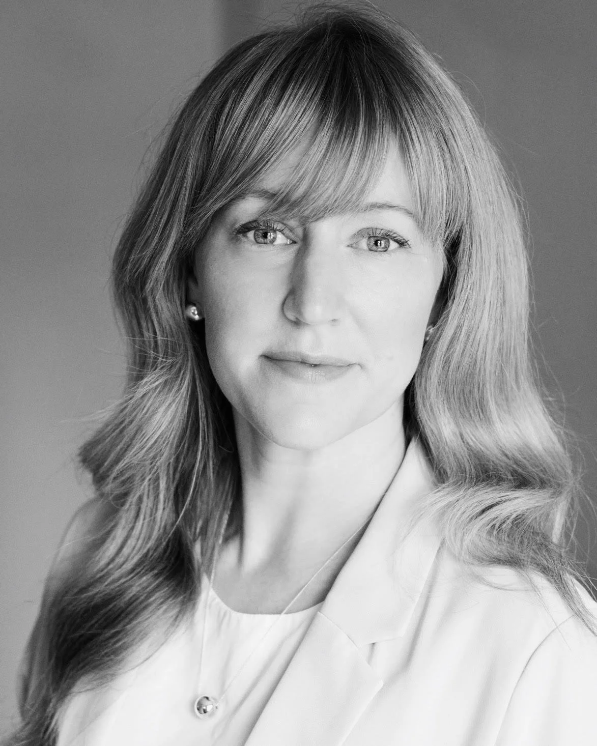 black and white professional headshot of a woman staring into the camera.
