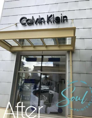 Calvin Klein store entrance with glass doors and yellow awning, maintained by painters offering commercial painting services and free estimate near you.