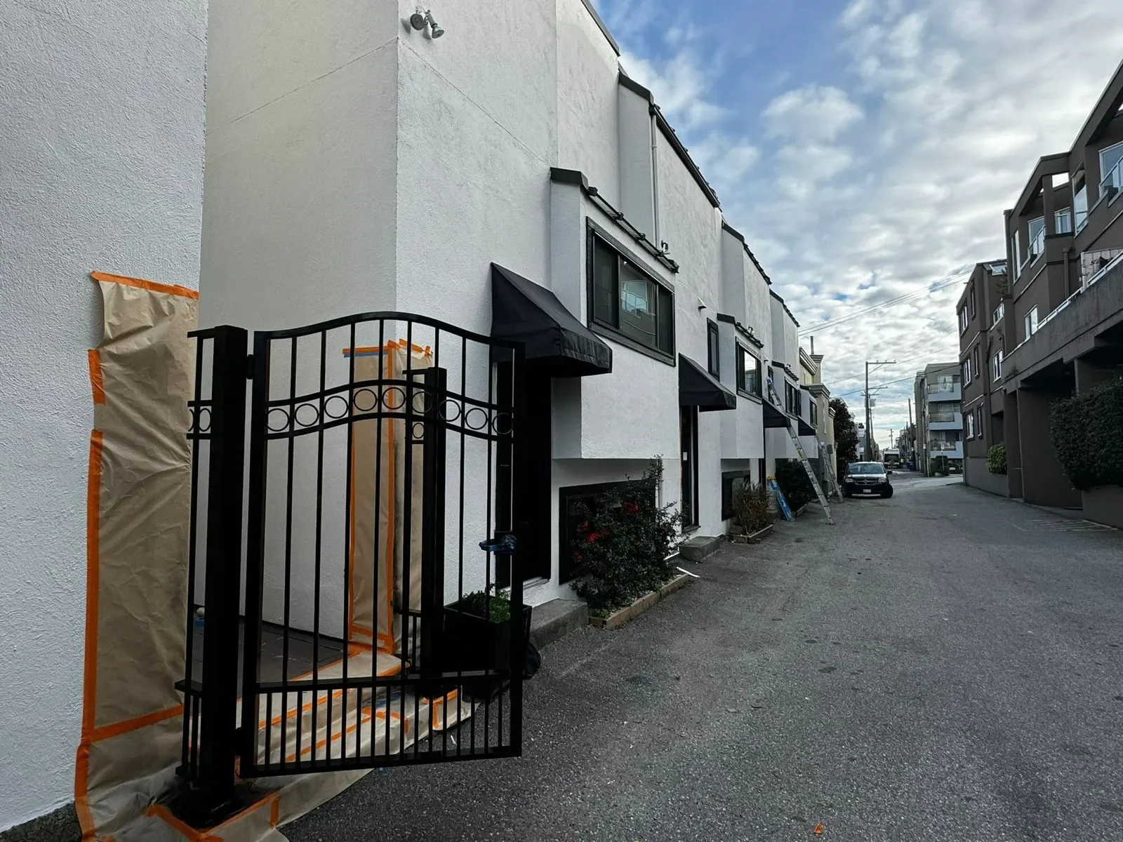 Professional painters working on a white apartment building exterior with black awnings, offering free painting estimate and exterior painting services near you.