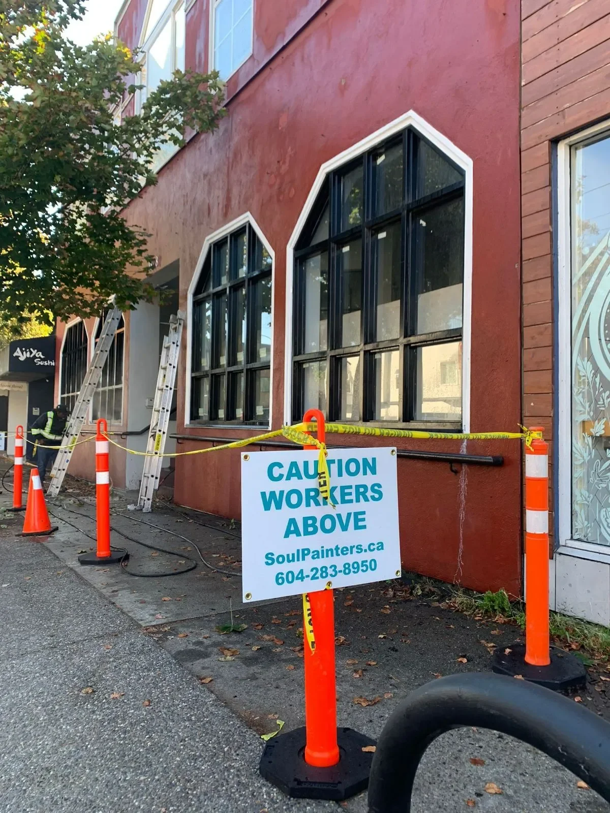 Professional painters on ladders working on a red commercial building exterior, offering free painting estimate and exterior painting services near you.
