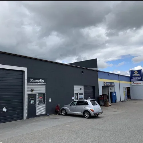 Soul Painters working on the exterior of a gray commercial auto repair shop with blue and yellow signage and a parked silver car, offering free painting estimate and exterior painting services near you.