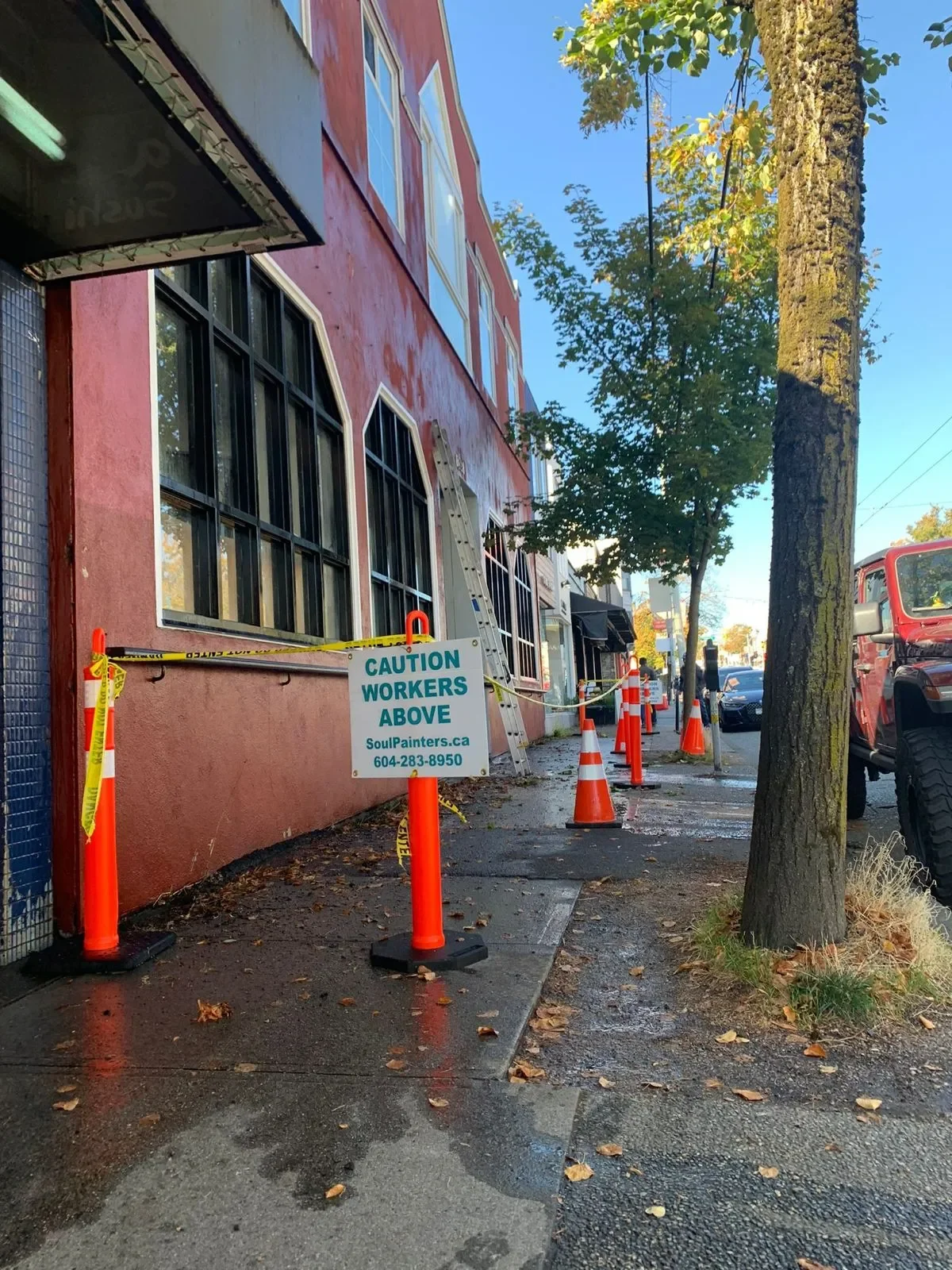 Professional painters working on a pink building exterior with ladder, caution cones, and arched windows, offering free painting estimate and exterior painting services near you.