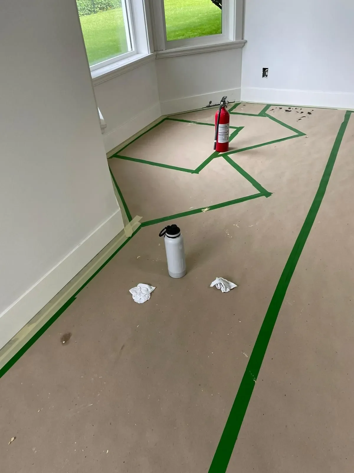 Room under renovation with painter’s tape creating geometric patterns on the floor, painted by professional painters offering free painting estimate and interior painting services near you.