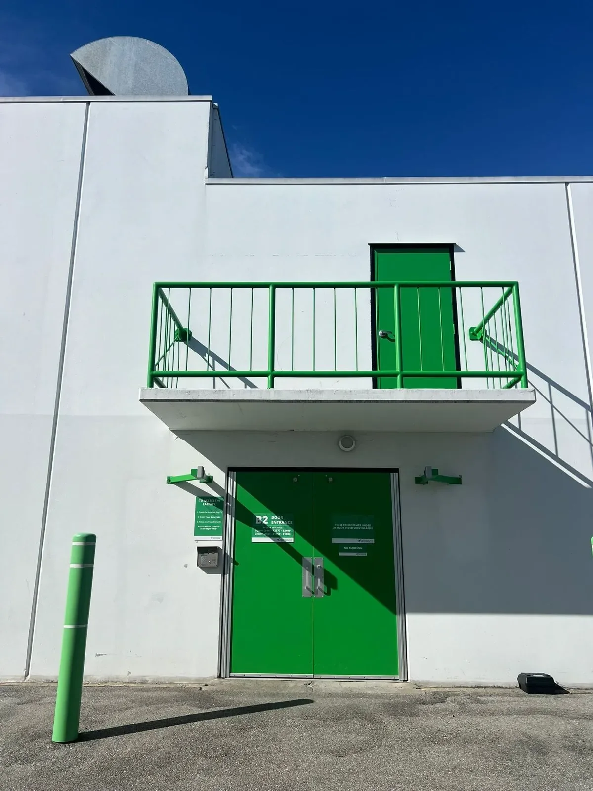 Professional painters working on a white building exterior with green door and balcony railing, offering free painting estimate and exterior painting services near you.