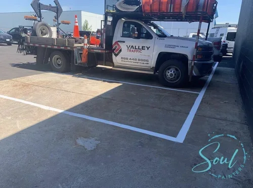 Valley Traffic control truck parked in marked space outside during daytime, with orange traffic cones and large spool of wire on bed, maintained by painters offering exterior painting services and free estimate near you.