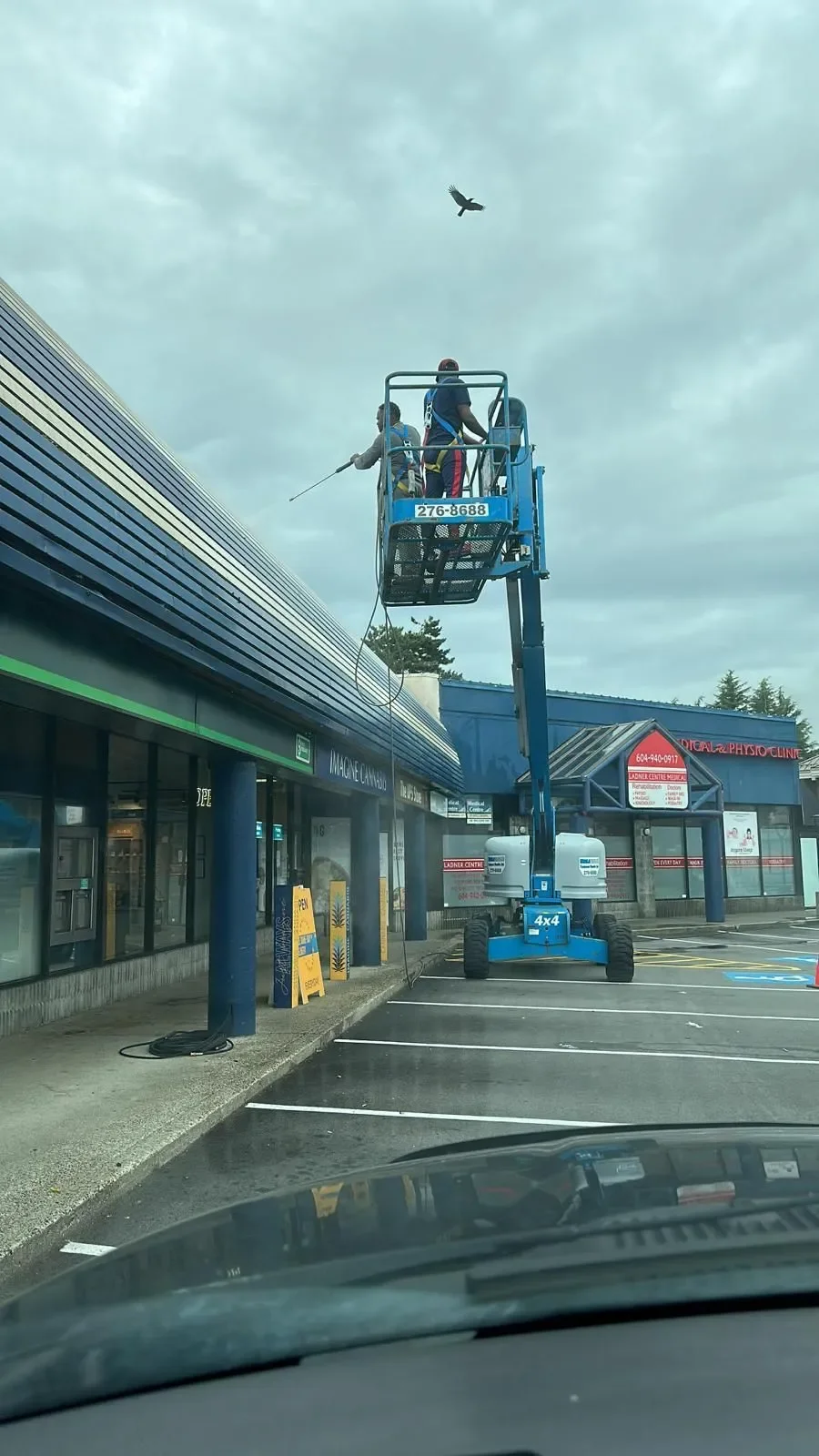 Professional painters on a blue lift repairing the exterior of a commercial building, offering free painting estimate and exterior painting services near you.