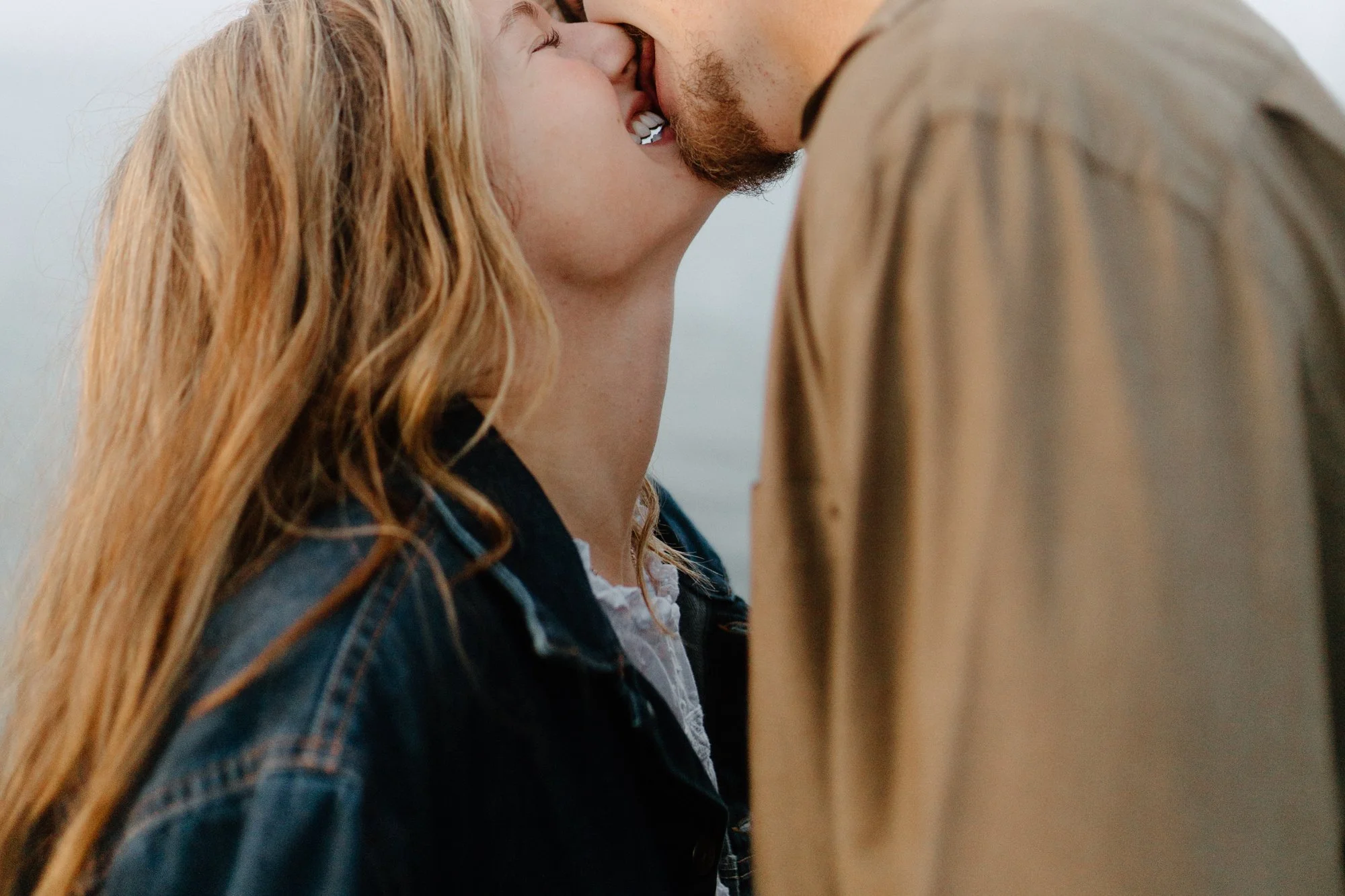 A close-up scene of a couple kissing outdoors, with their faces very close and only part of their heads and shoulders visible.