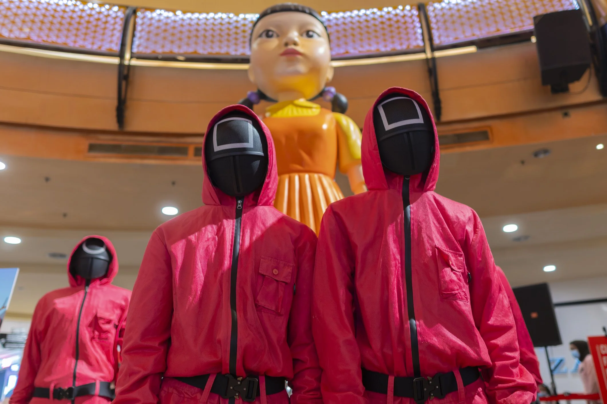 Screen Grab of Squid Games doll and Workers in red suits