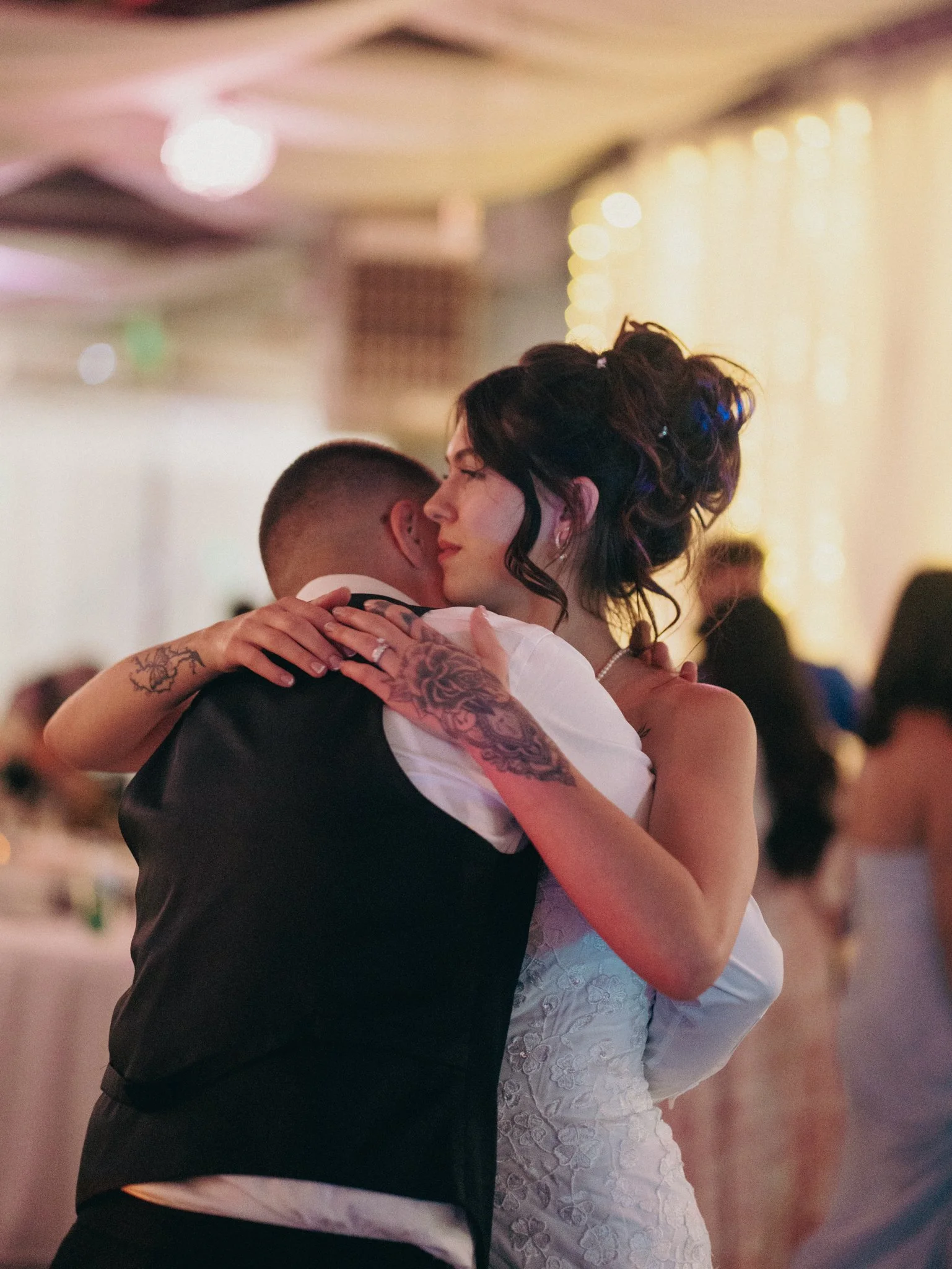 A bride and groom sharing a dance at their wedding reception, embracing each other closely with a warm and emotional expression.