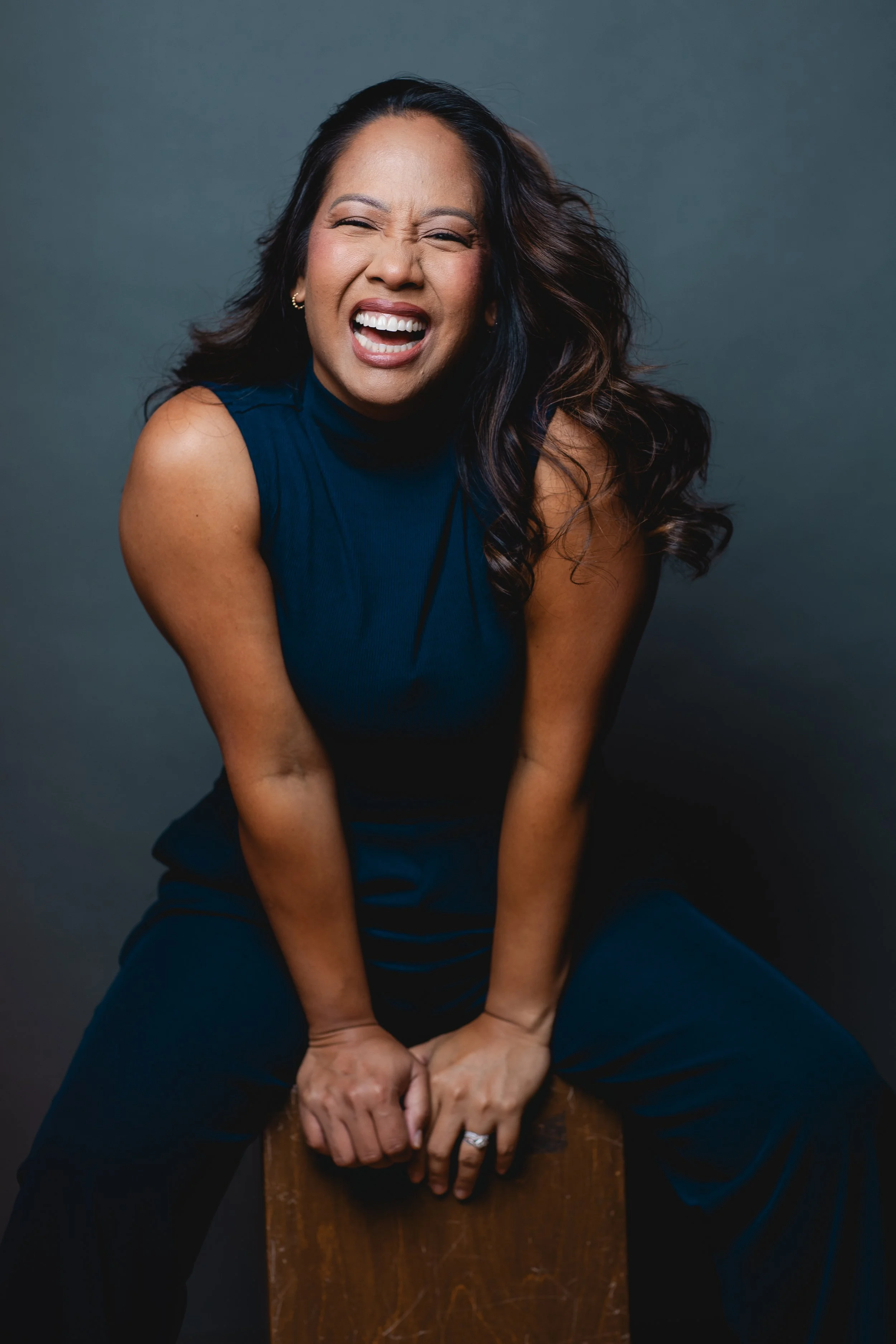 Joanne sitting with arms in front and a big smile.