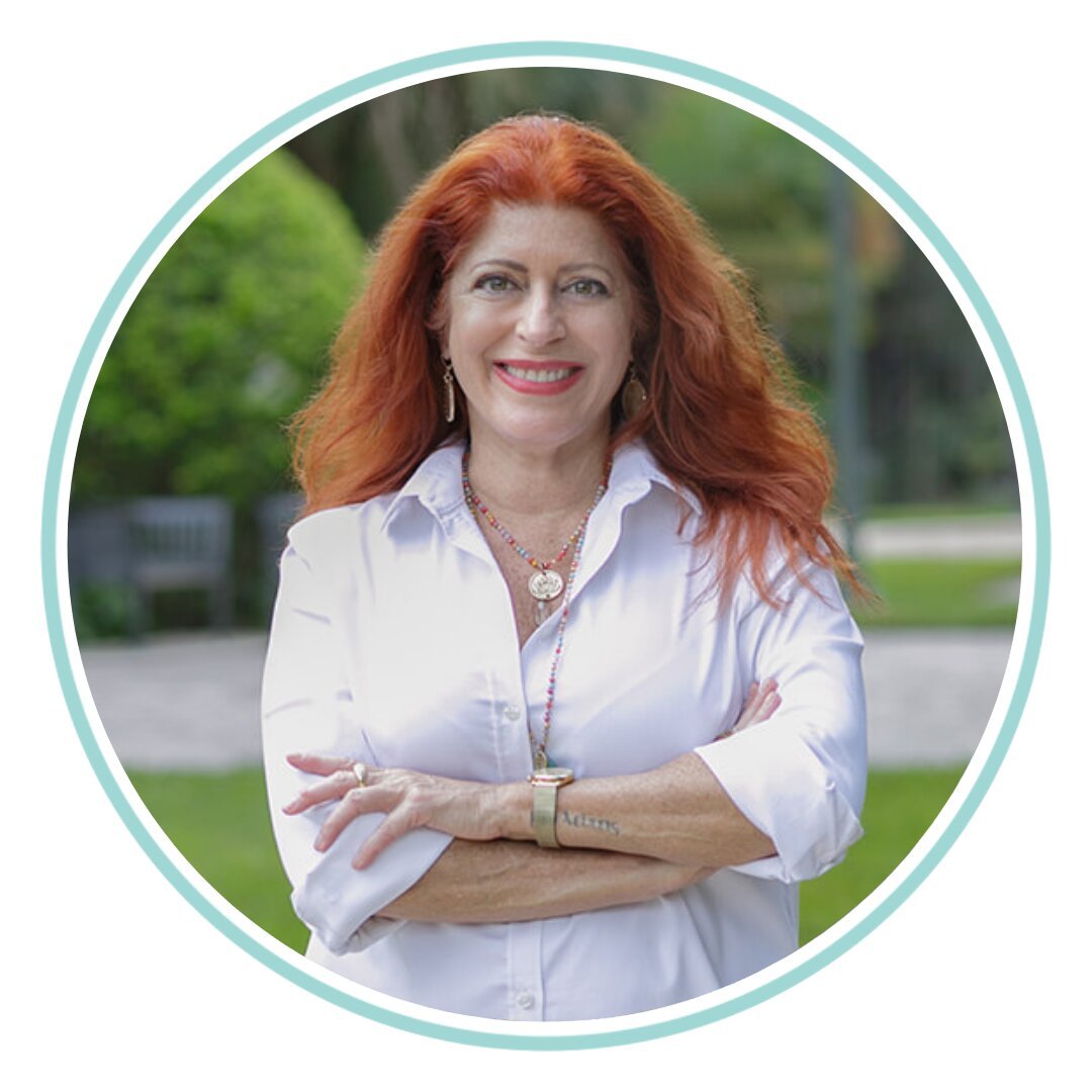 woman with red hair and white shirt standing outside with arms crossed