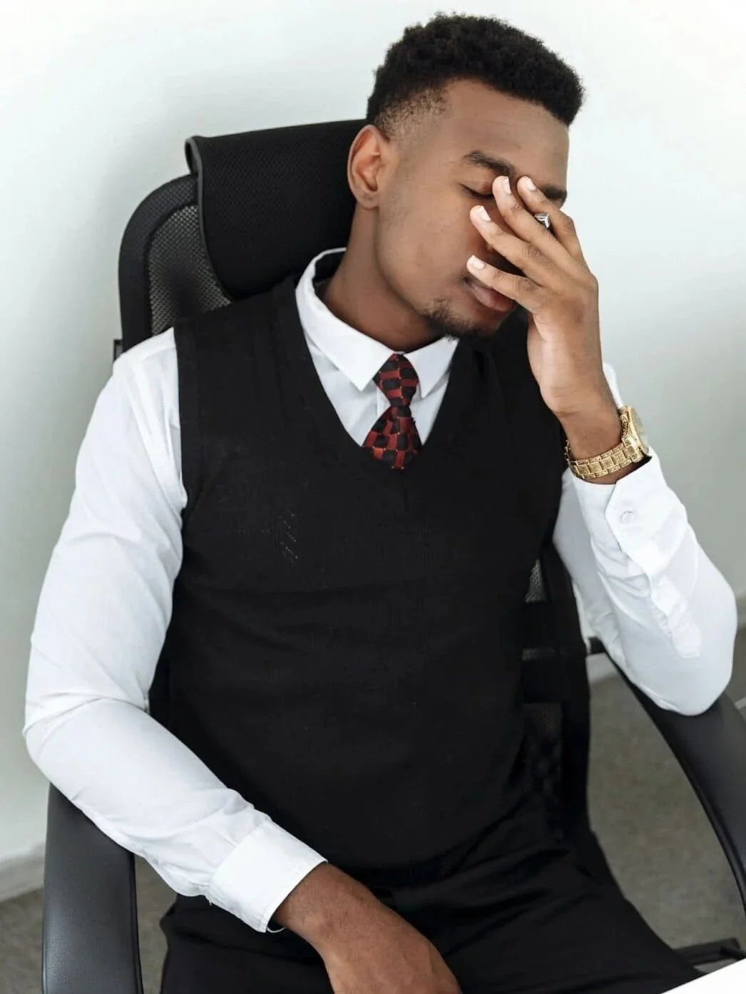 man in a suit covering his face with his hand