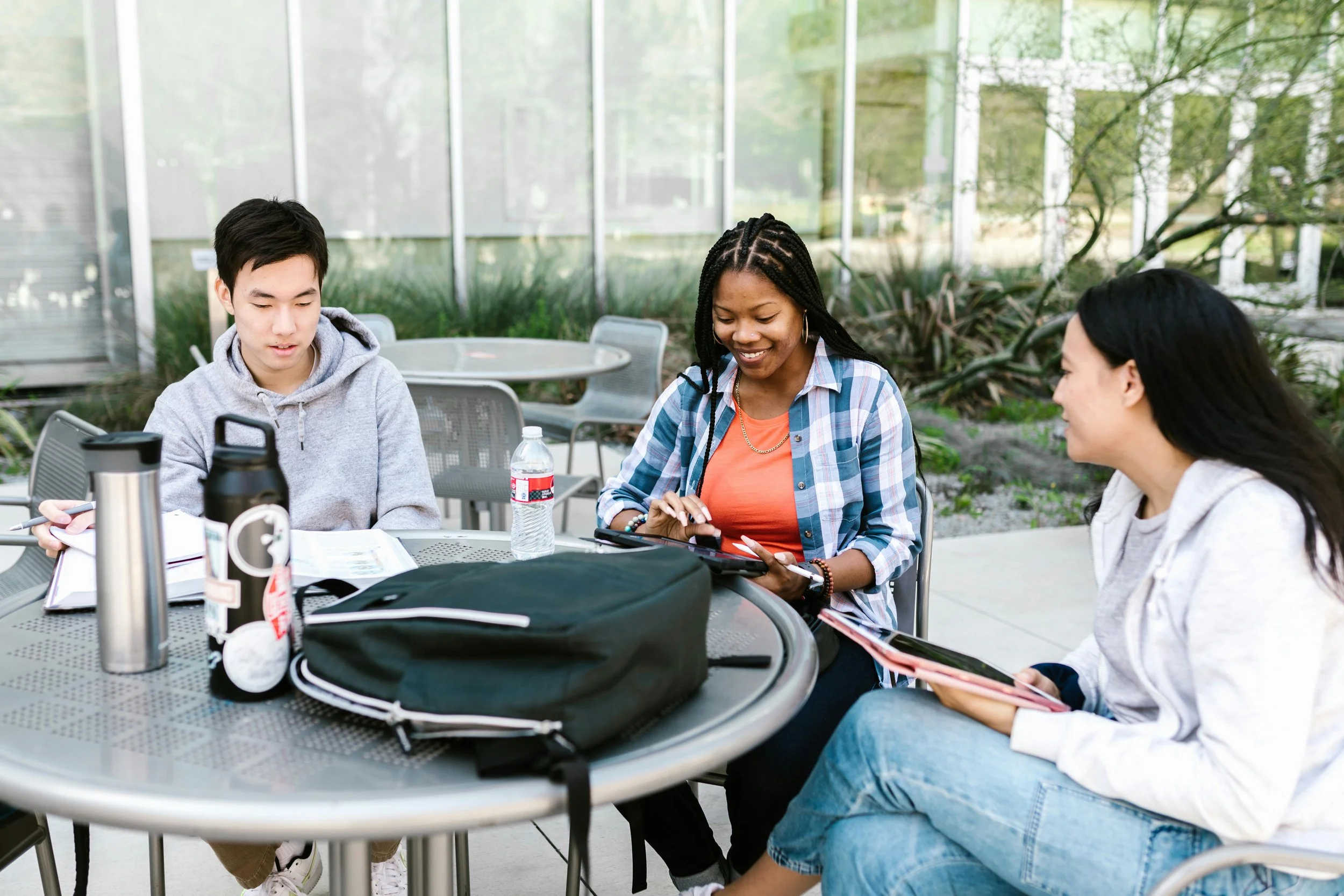 Diverse group of teens studying together outdoors with notebooks and tablets, reflecting teen college prep and peer support for academic success.