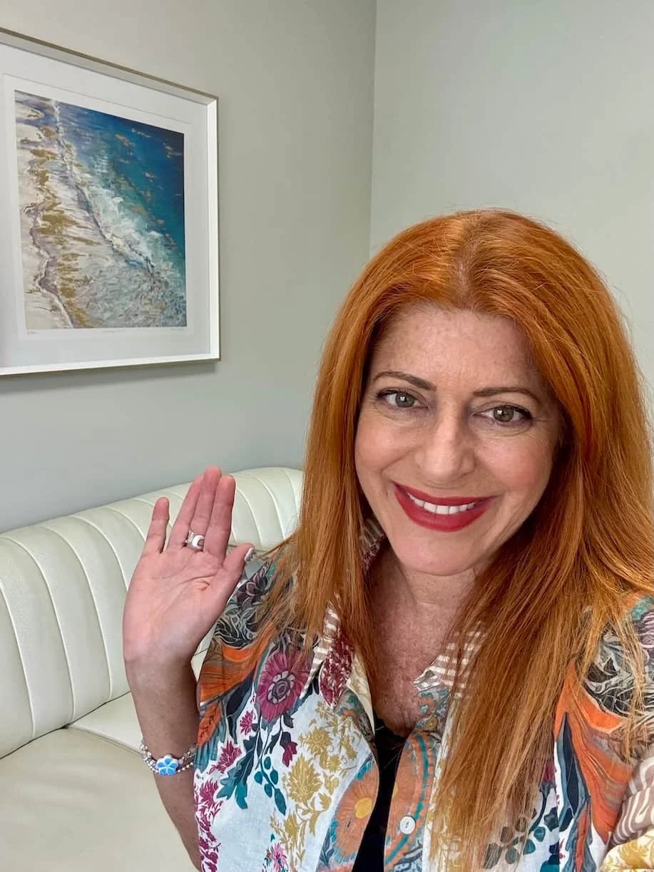 woman with red hair and colorful top smiling