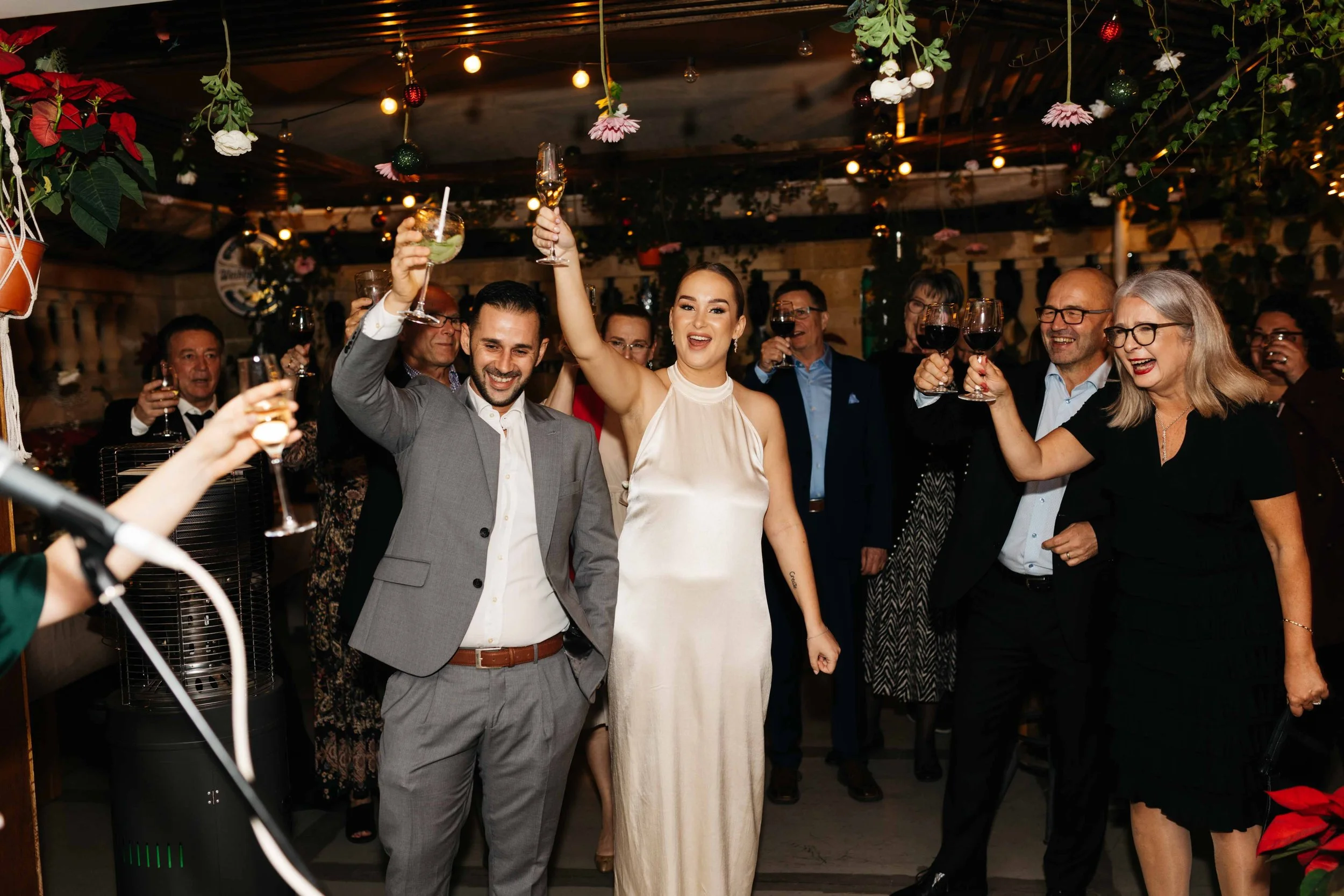 Group celebrating with raised glasses at a party in a decorated room.