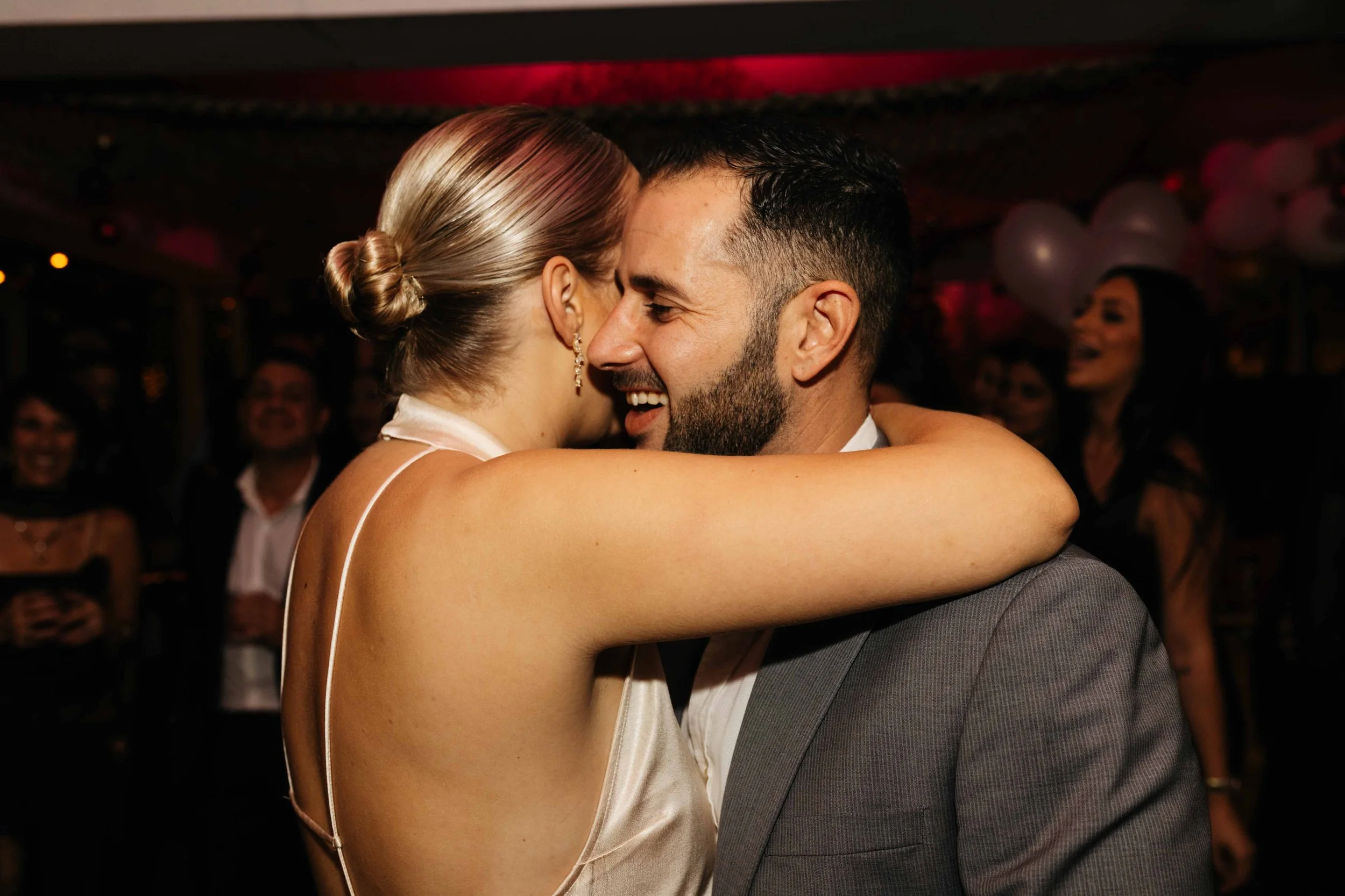 Couple dancing at a party with people in the background