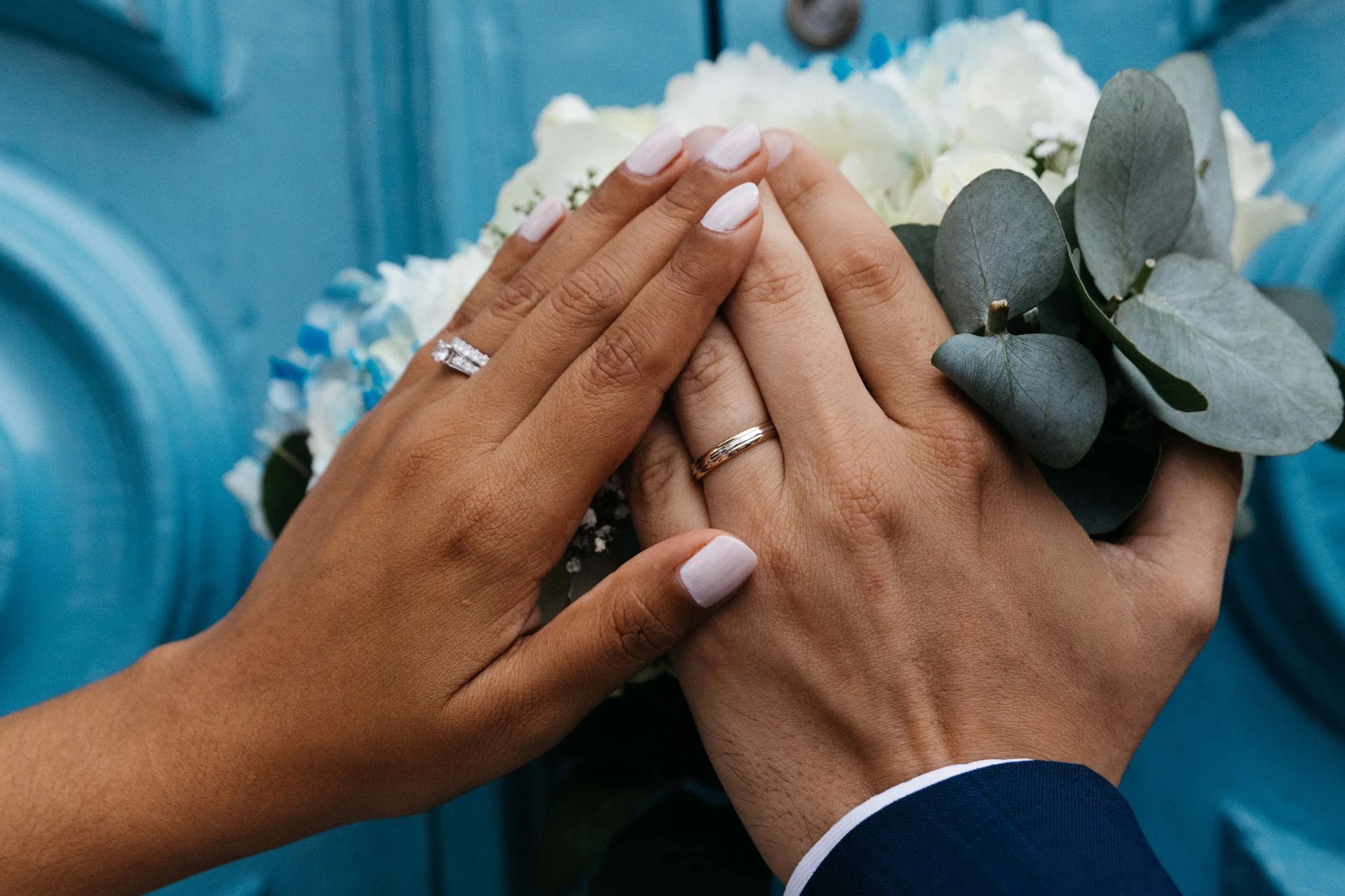Couple's hands with wedding rings and flowers