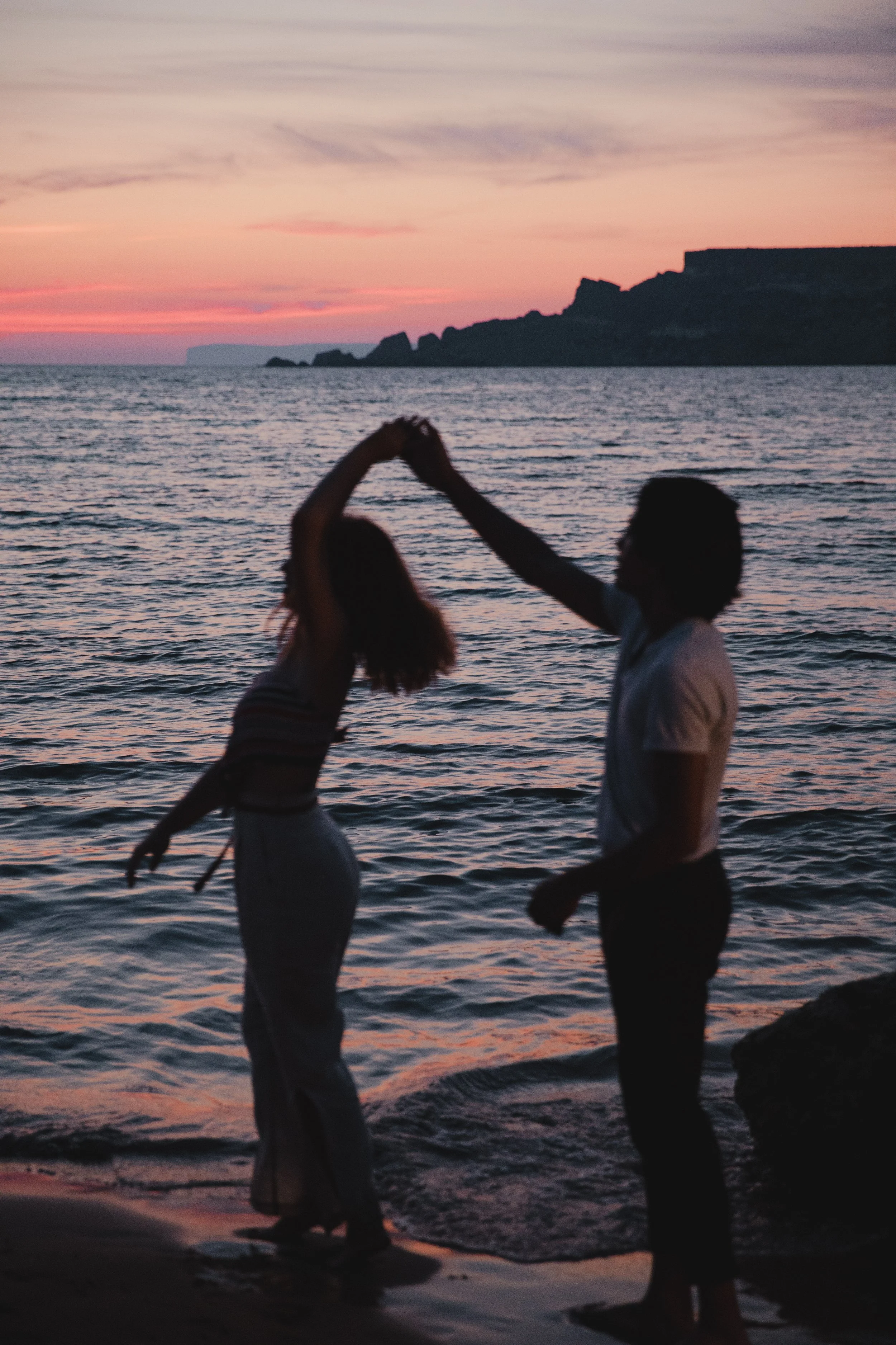 Silhouette of a couple dancing on a beach at sunset.