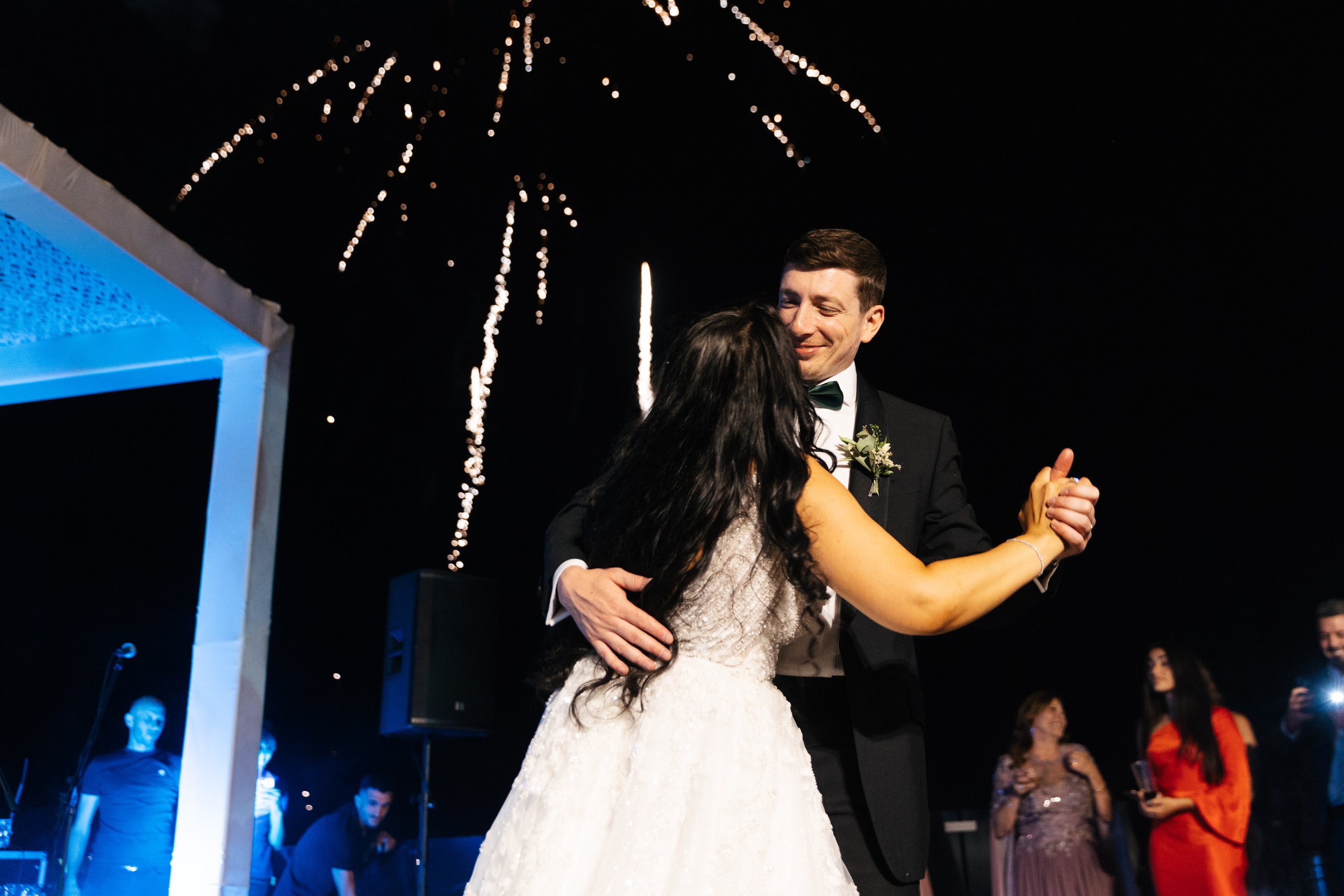 Bride and groom dancing under fireworks at night