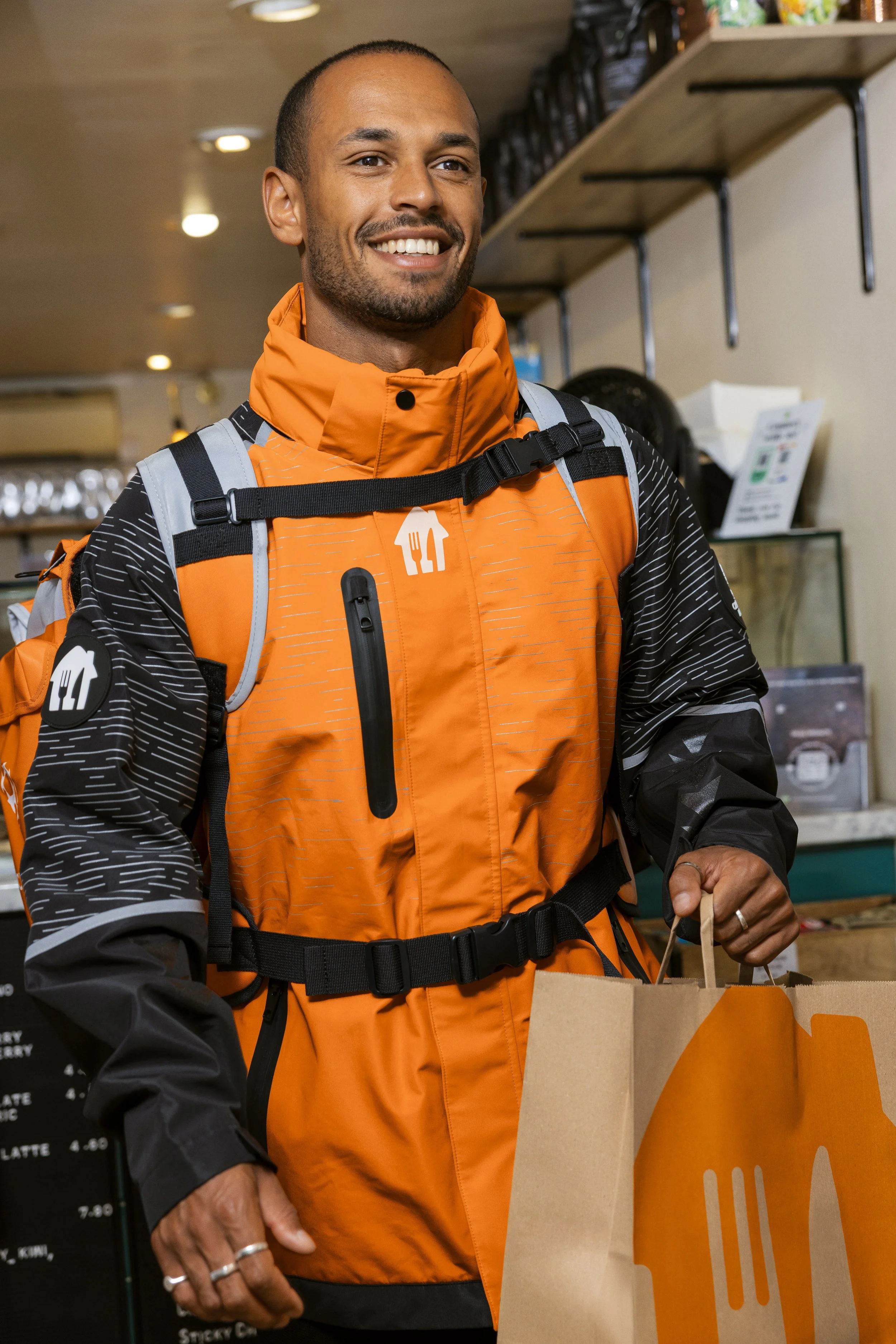 Just Eat campaign: a courier smiling as he collects an order bag, photographed by Dean Bartolo.