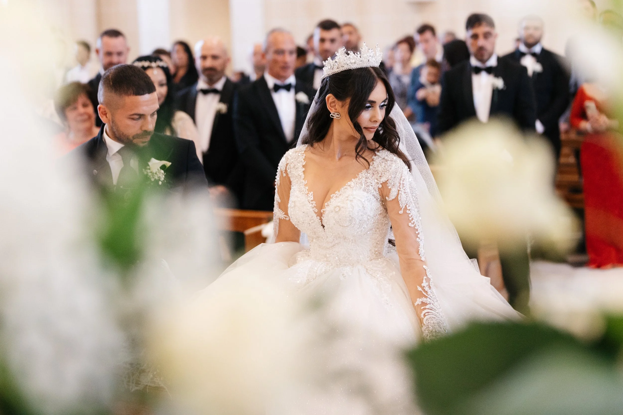 Bride and groom at wedding ceremony with a crowd and floral decorations.