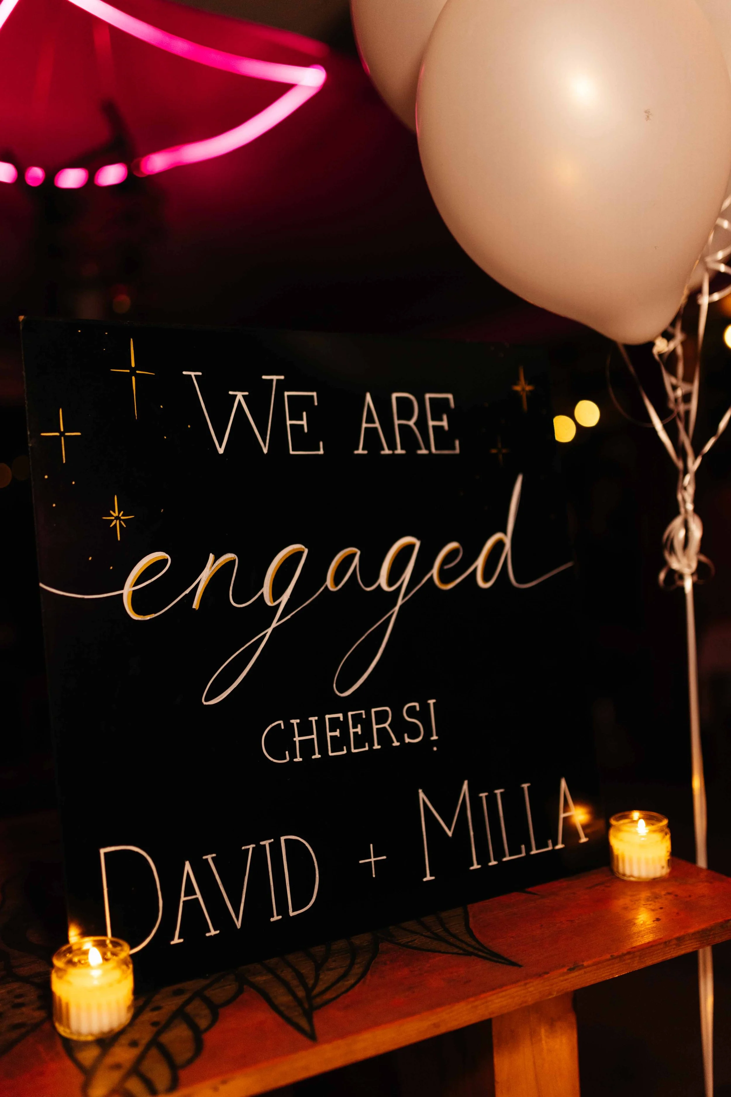 Engagement announcement sign with candles and balloons